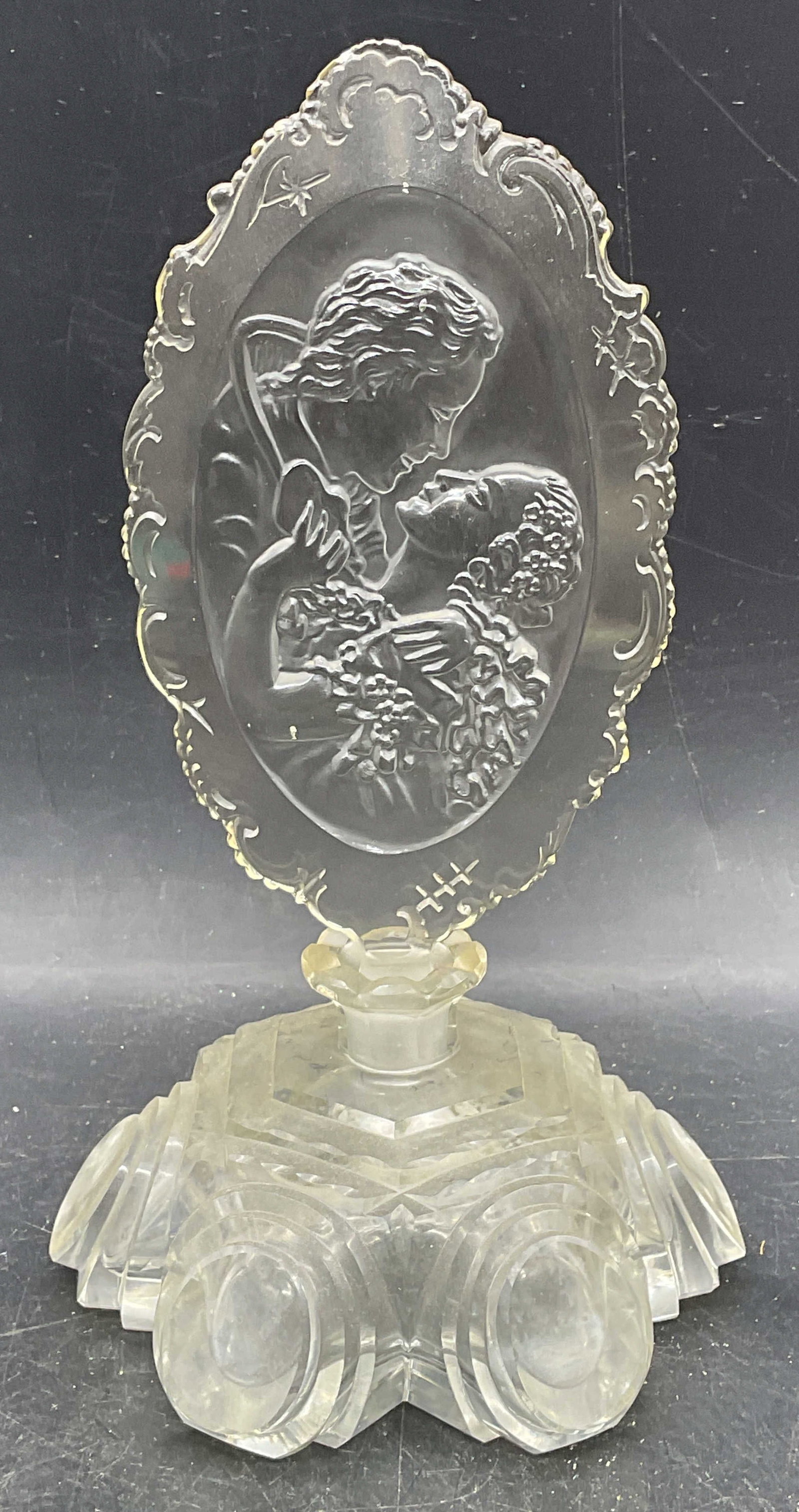 Vintage Cut Glass Ornate Couple Perfume Bottle: Vintage cut glass perfume bottle with geometric design and ornate cut glass stopper with courting couple motif. Bottle measures approx. 5 x 5 x 2.75 inches. Stopper measures approx. 3.5 x 8.25 inches.