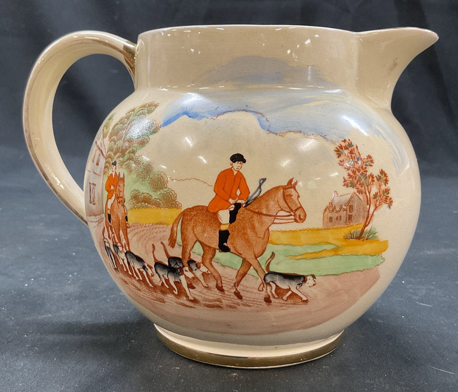 Sadler Painted Hunting Scene Pitcher England: Sadler painted hunting scene ceramic pitcher. Marked on underside, reads Sadler Made In England. Hand painted landscape scene of figures on horses hunting with foxes and hounds. Gilt trim. Curved spou