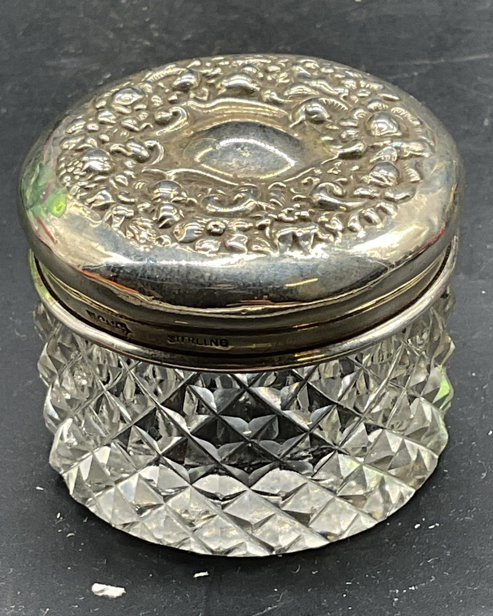 Vtg Signed Sterling Silver & Cut Glass Powder Jar: Vintage sterling silver lidded cut glass powder jar. Diamond pattern jar with ornate repousse lid. Marked sterling. Signed with makers mark. Measures approx. 1.75 x 1.25 inches. Total weight of sterli