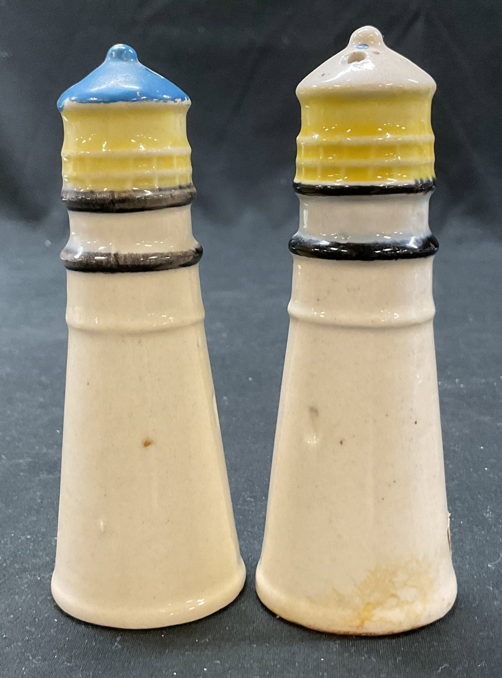 Vtg Ceramic Lighthouse Salt & Pepper Shakers Japan: Vintage ceramic lighthouse salt and pepper shakers. Marked Japan on underside. Tall cylinder shape with small finial. Painted blue, yellow, cream, and black. Glossy finish. Measures ht approx 4