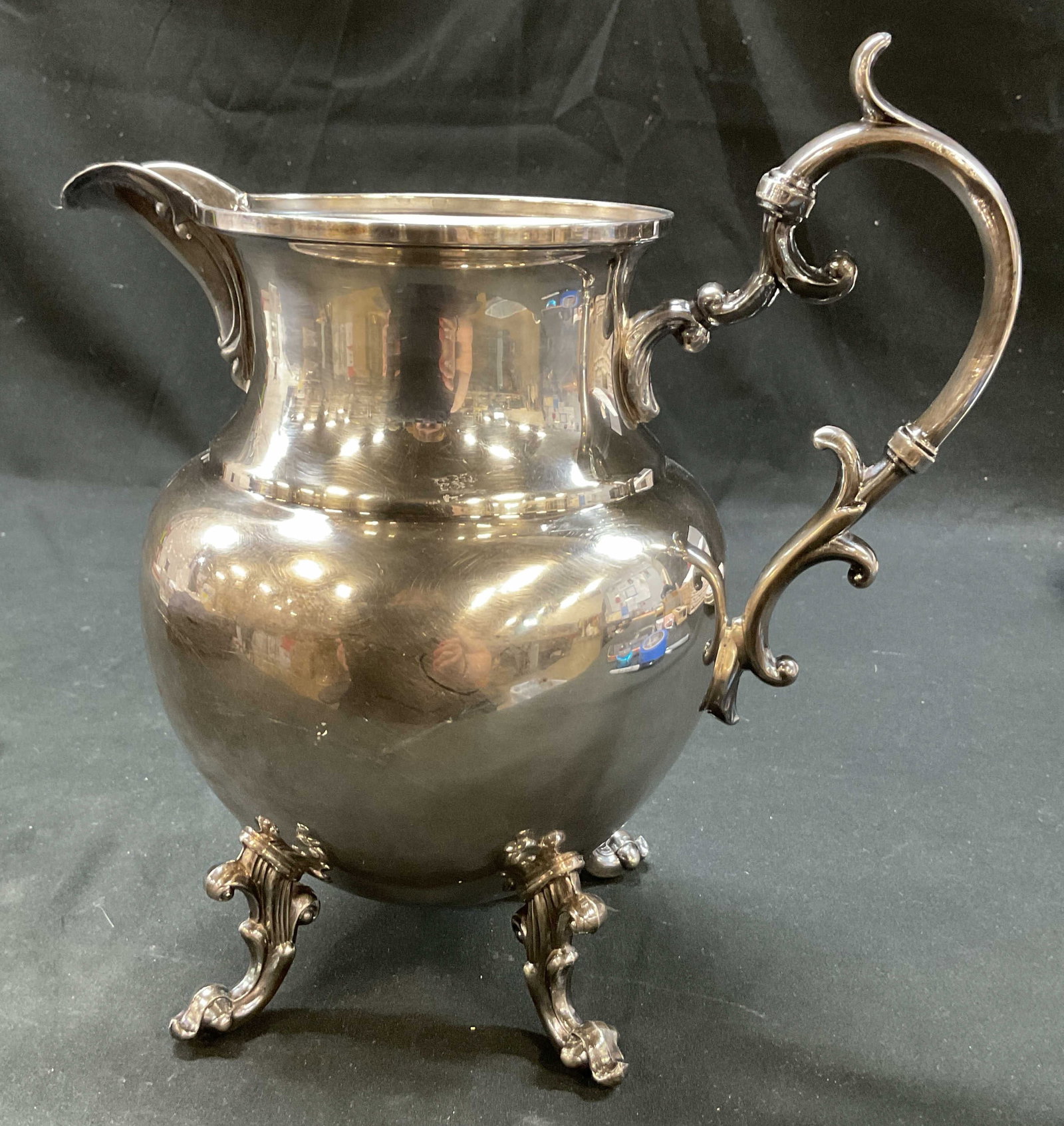 Birmingham Silver Co Silver On Copper Pitcher: Birmingham Silver Co silver on copper footed pitcher. Marked on underside, reads Silver On Copper BSC. Four ornate designed feet on underside. Curved scroll handle and curved spout. Bulbous body. Meas