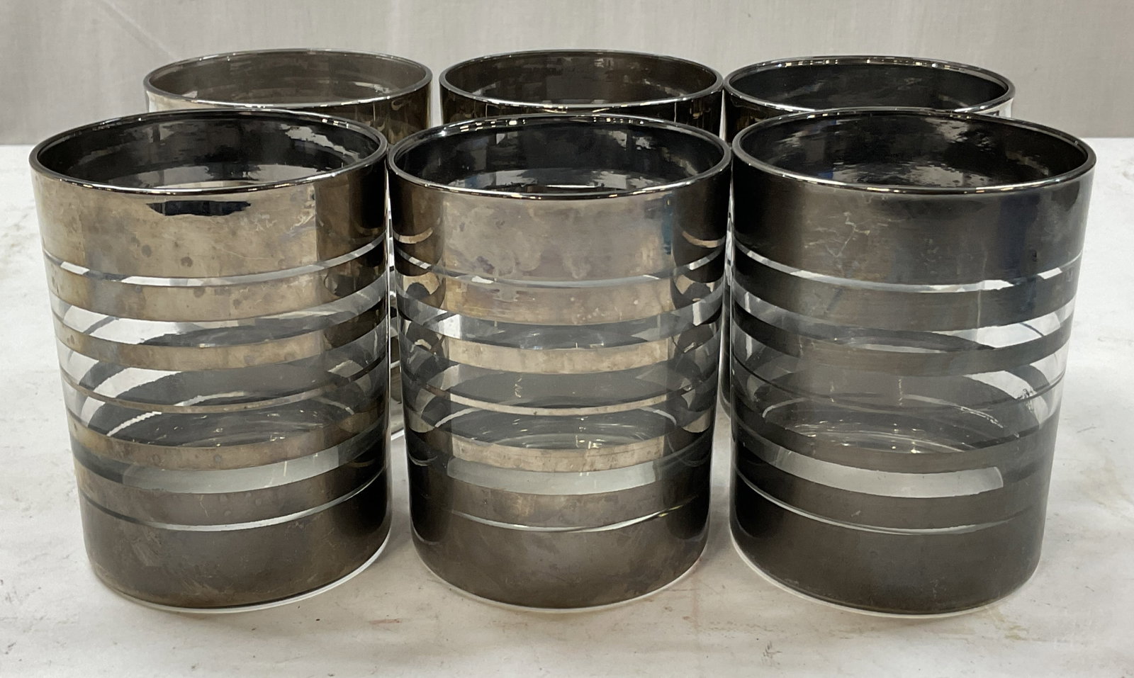 Set 6 Vintage Silver Plated Band Lowball Glasses: Set of 6 vintage silver plated band lowball glasses. Cylindrical shape. Silver plated band design. Measures ht approx 4 inches diam approx 3.5 inches. Scratching and wear. Lowball glasses, tumblers,