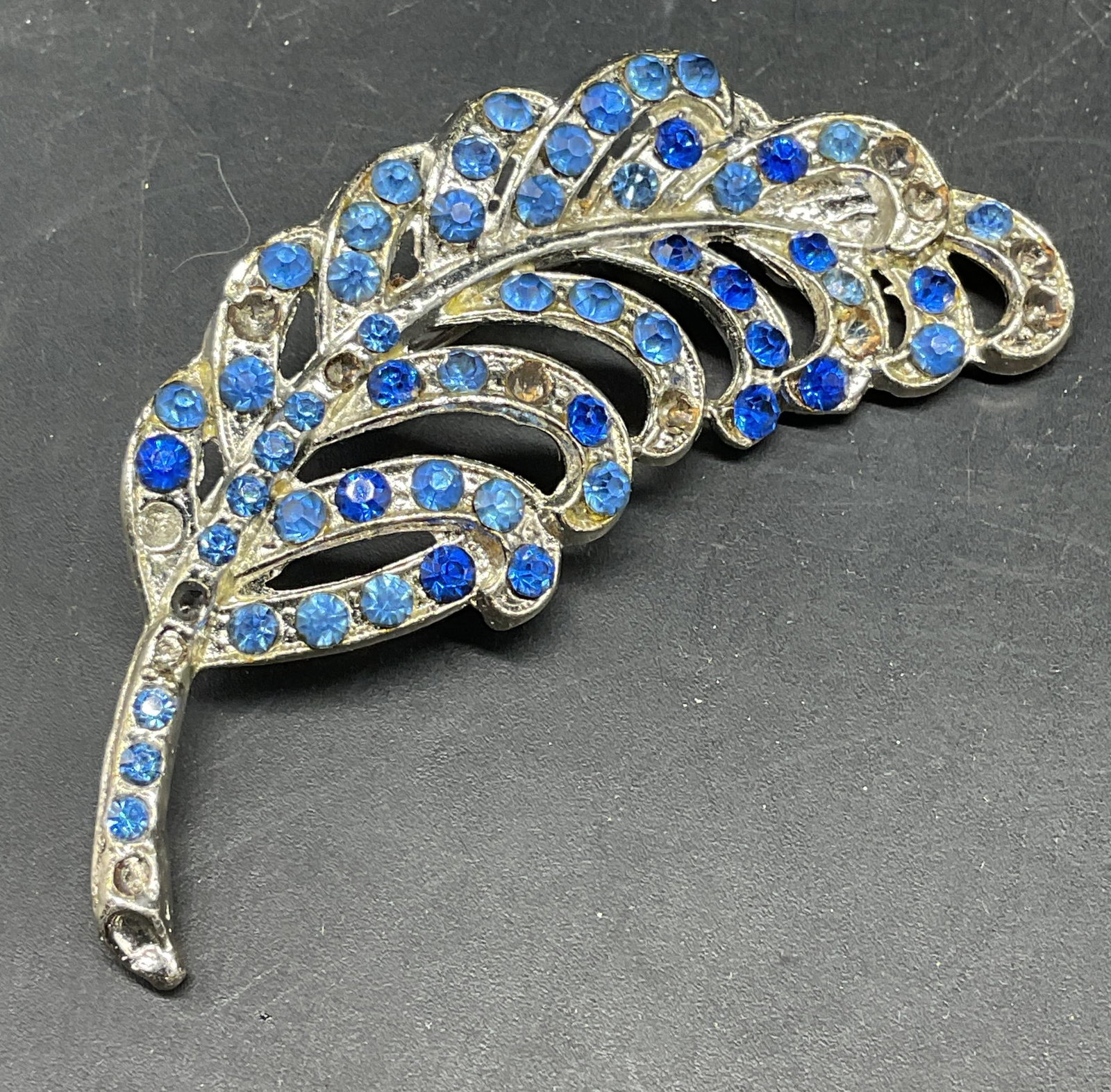 Vtg Silver Tone Blue Crystal Feather Brooch: Vintage silver tone blue crystal feather brooch. Measures approx. 2.75 x 1.25 inches. Some crystals need replacement. Some scratching. Jewelry, estate jewelry, costume jewelry, cocktail jewelry,