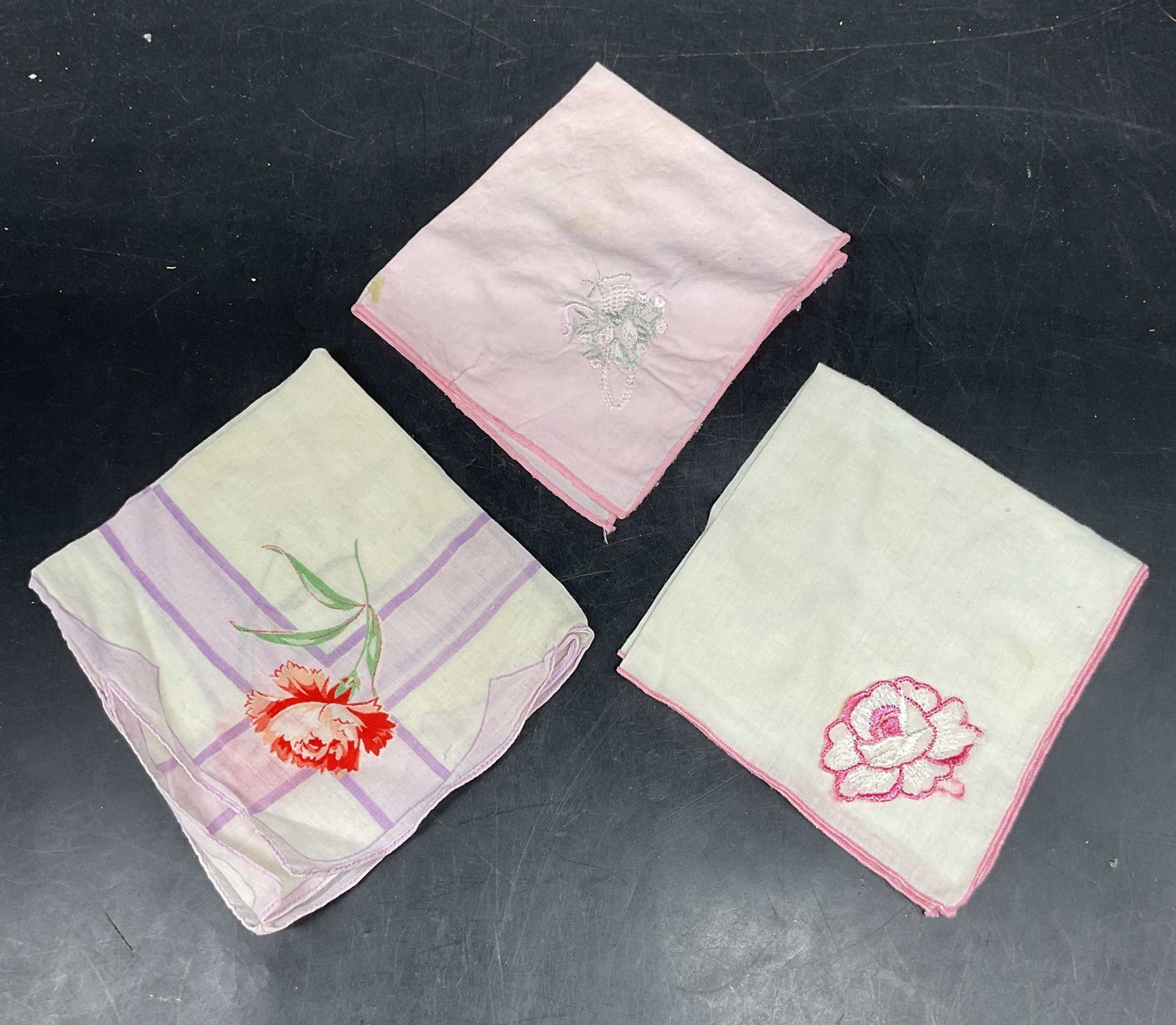 Lot 3 Vtg Pink & White Floral Handkerchiefs: Lot of 3 vintage pink, white, and purple cotton handkerchief. White embroidered, pink floral embroidered, purple floral print designs. Largest measures approx. 11 x 10 inches. Some blemishes and wear 