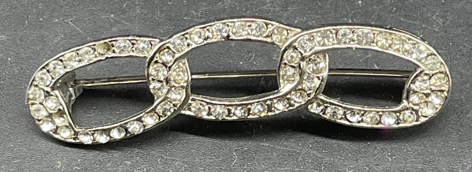 Vintage Silver Tone Crystal Chain Link Brooch: Vintage silver tone colorless crystal chain link motif brooch. Measures approx. 2 x .5 inches. Some scratching. Some crystals need replacement. Jewelry, estate jewelry, costume jewelry, cocktail jewel