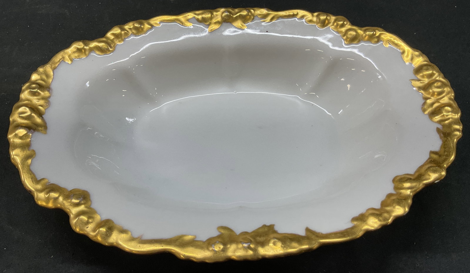 J. Pouyat Limoges Porcelain Bowl France: J. Pouyat Limoges porcelain bowl. Marked on underside, reads J.P. L France. Oval shaped bowl. Embossed scalloped gilt edge. Measures ht approx 2 inches diam approx 9 inches. Surface wear consistent wi