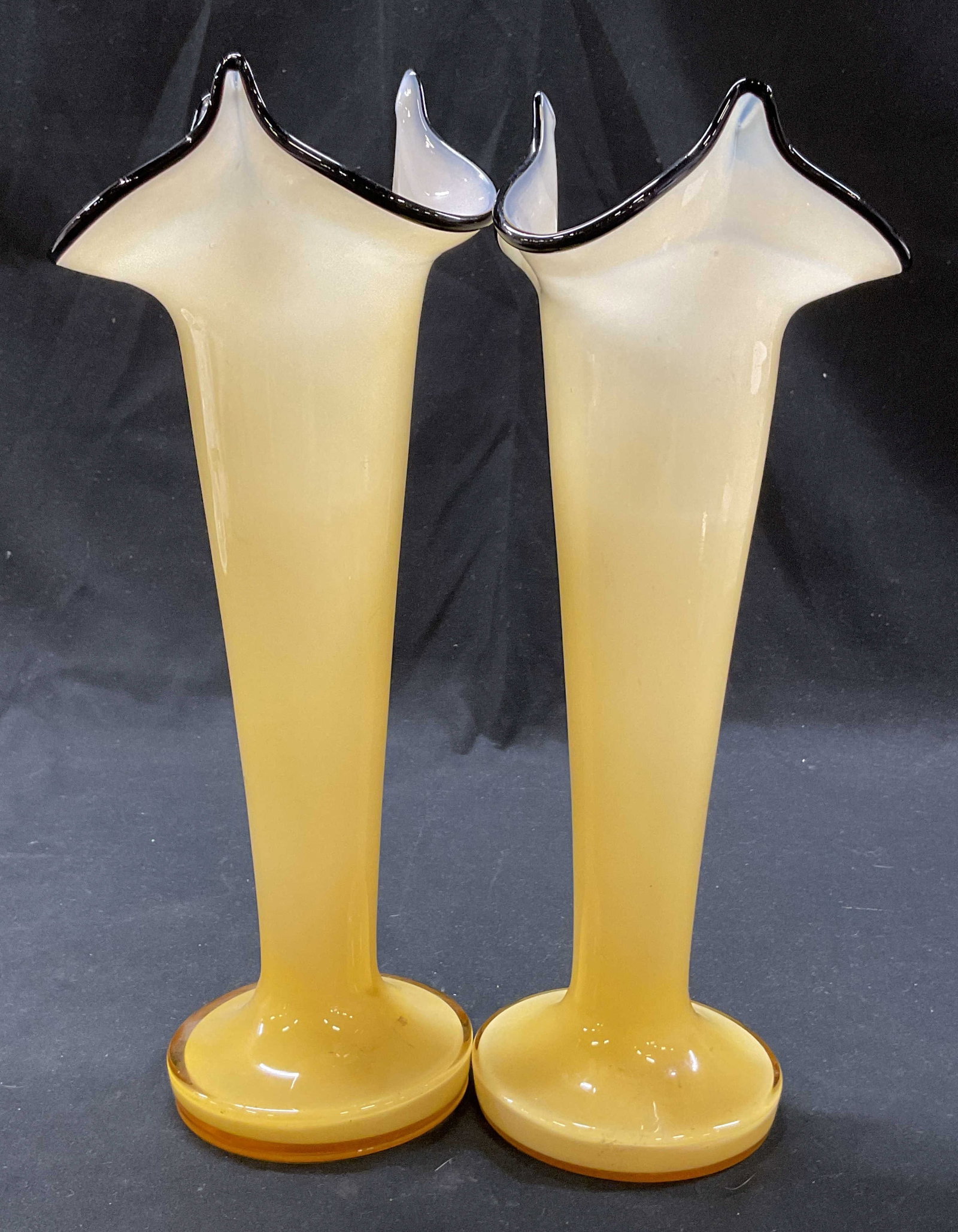Pair Hand Blown Yellow Ruffled Art Glass Vases: Pair of hand blown yellow ruffled art glass vases. Round base. Ruffled and scalloped black rim. Yellow body. Measures ht approx 10.5 inches diam approx 3.5 inches. Surface wear consistent with exposur