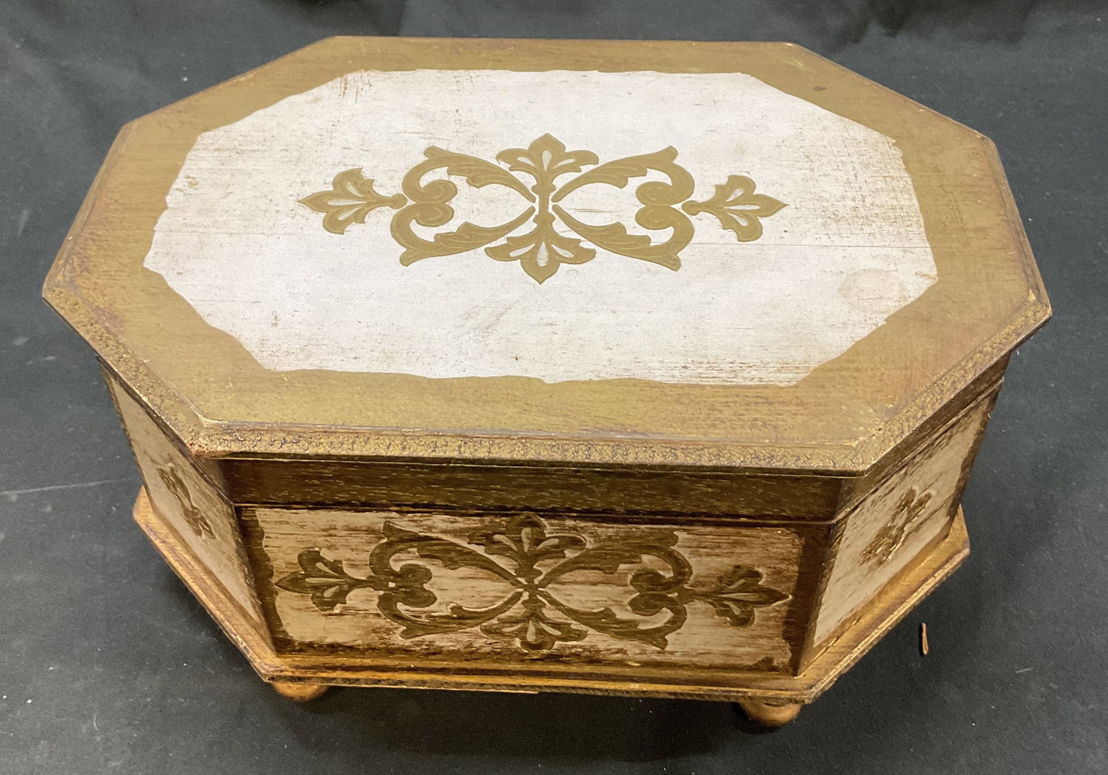 Vintage Wooden Footed Jewelry Music Box: Vintage wooden footed hinged jewelry music box. Four feet on underside. Octagonal shape. Carved scroll and floral motifs. Gilt accents. Red lining with fitted compartments. Mirror on interior. Hinged