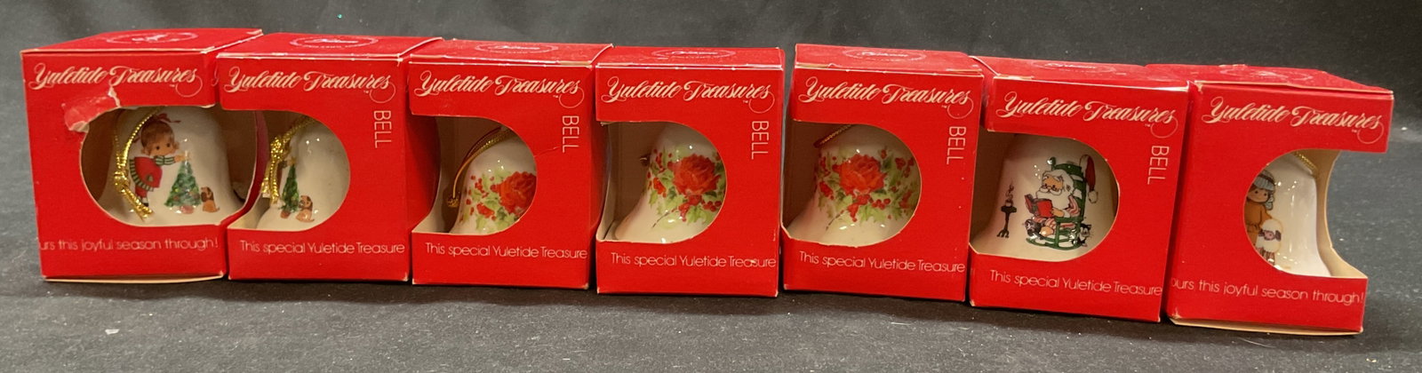 Lot 7 Gibson Yuletide Treasures Bell Ornaments NIB: New in box. 7 Gibson Yuletide Treasures porcelain ornament bells. White bells with figural, floral, animal, Santa, and more motifs. Varying colors. Box measures approx 2.5 x 2.5 x 3 inches. Not