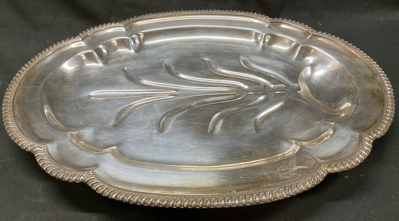 Vintage Silver Plated Footed Carving Tray 20in: Vintage silver plated footed carving tray. Ornate feet on underside. Scalloped braided edge. Distinct tree of life design for channeling juices. Measures approx 15 x 20 inches. Scratching. Carving