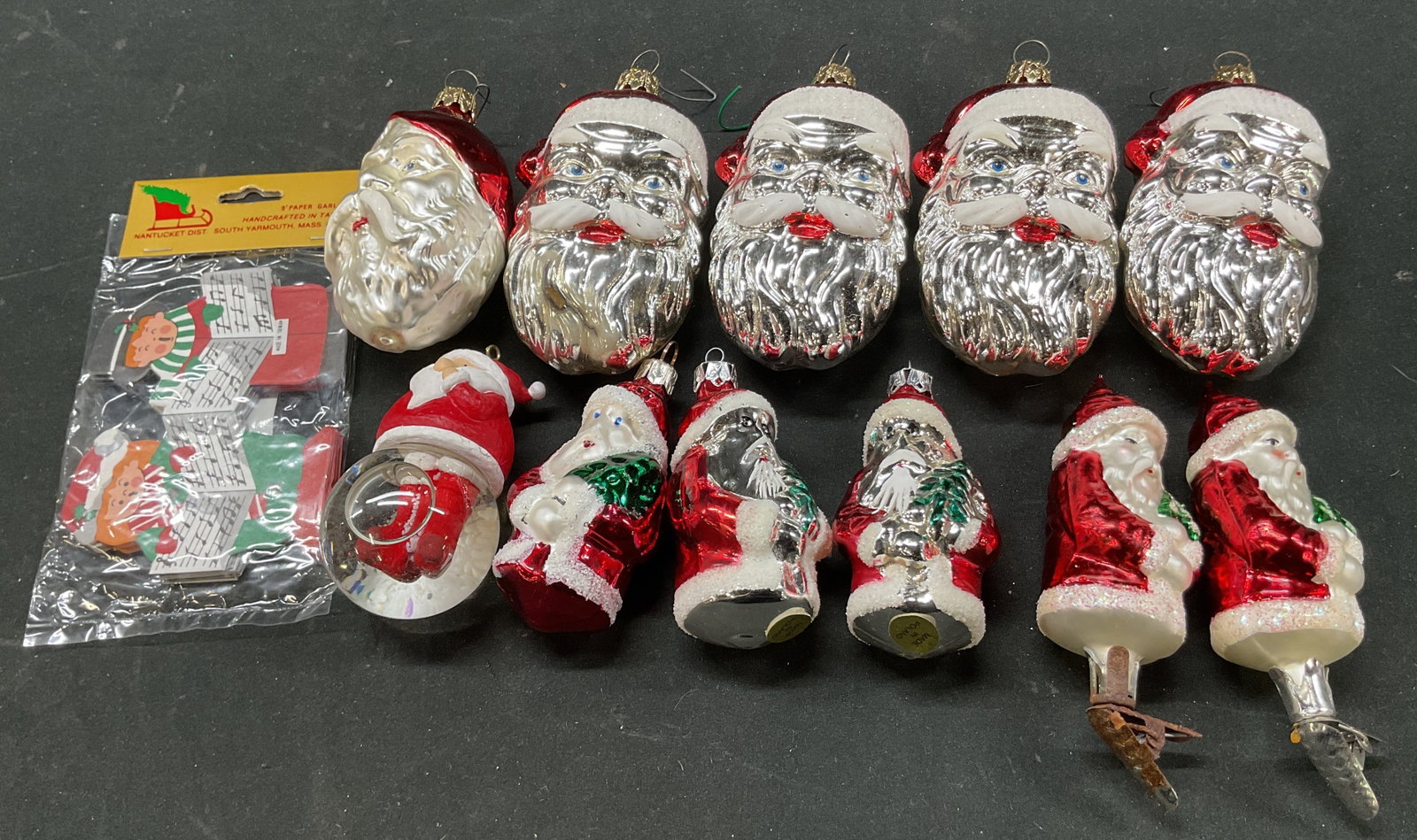 Grp Lot 12 Santa Ornaments & More Poland: Group lot of 12 assorted glass Santa ornaments. Some are marked made in Poland. Varying designs. One is shaped like a snow globe. Glitter accents. Red, white, green, silver toned. Lot also includes a