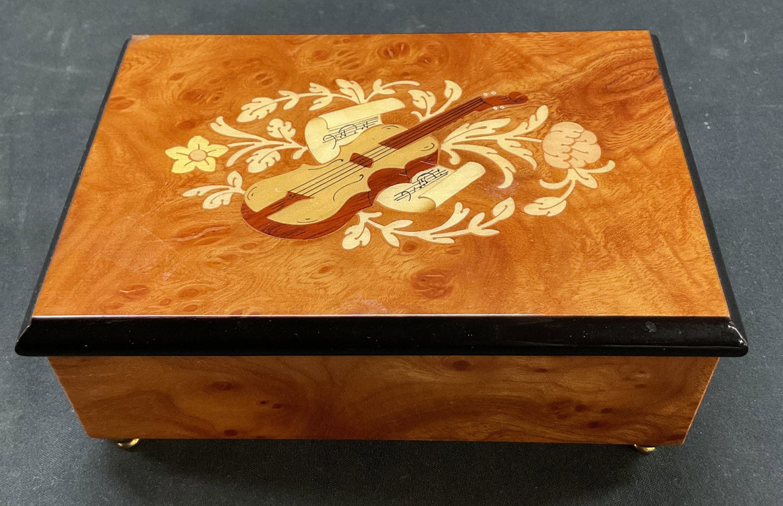 Bohme Music Jewelry Music Box Germany: Bohme Music wooden footed hinged jewelry music box. Marked on underside. Made in Germany. Footed on underside. Inlaid design of a violin surrounded by florals, varying colors. Red lining with fitted