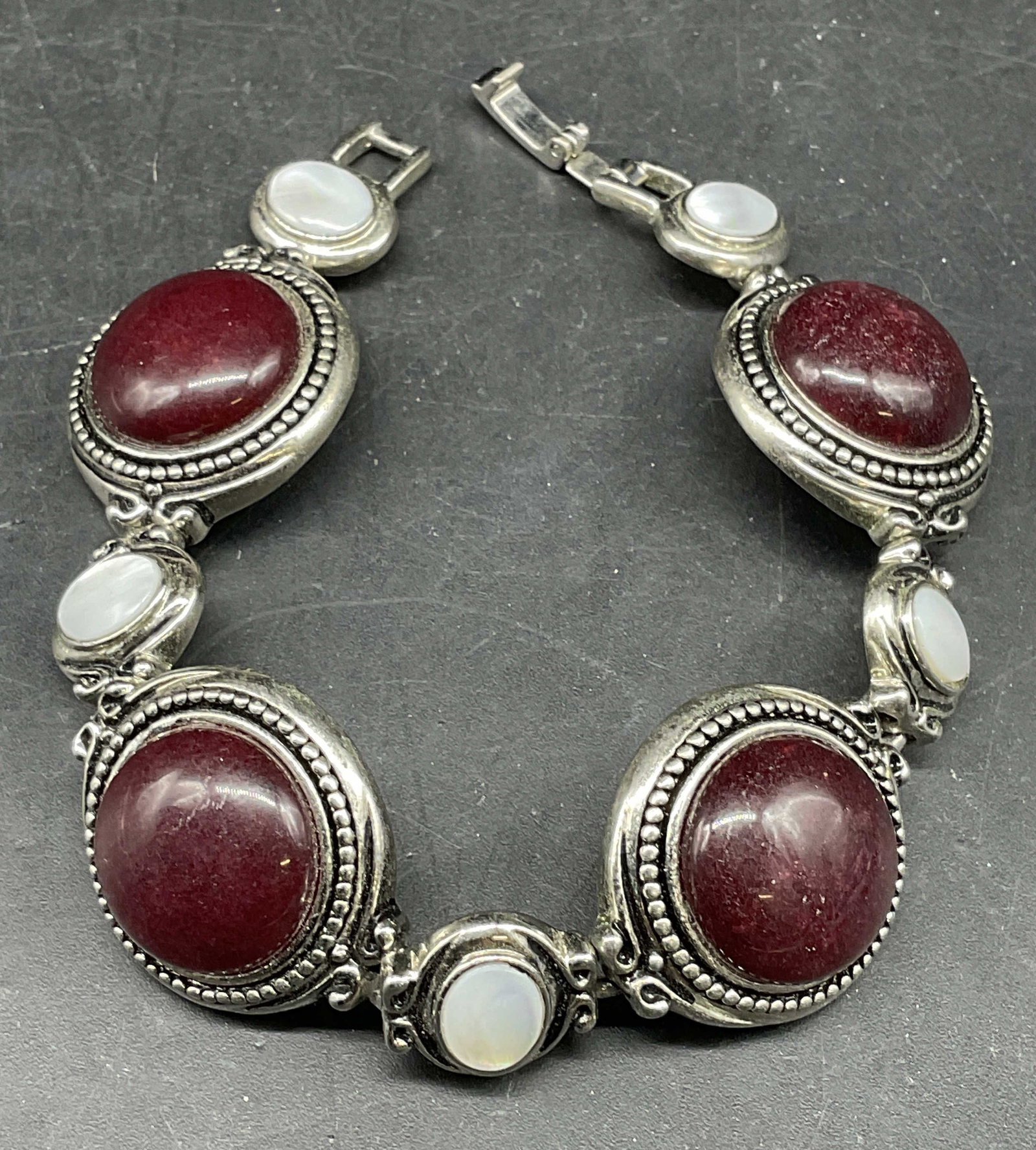 Lia Sophia Mother of Pearl Red Stone Bracelet: Lia Sophia silver tone bracelet with mother of pearl red stone cabochons. Measures approx. 7 inches. Some scratching. Jewelry, estate jewelry, costume jewelry, cocktail jewelry, fashion jewelry, acces