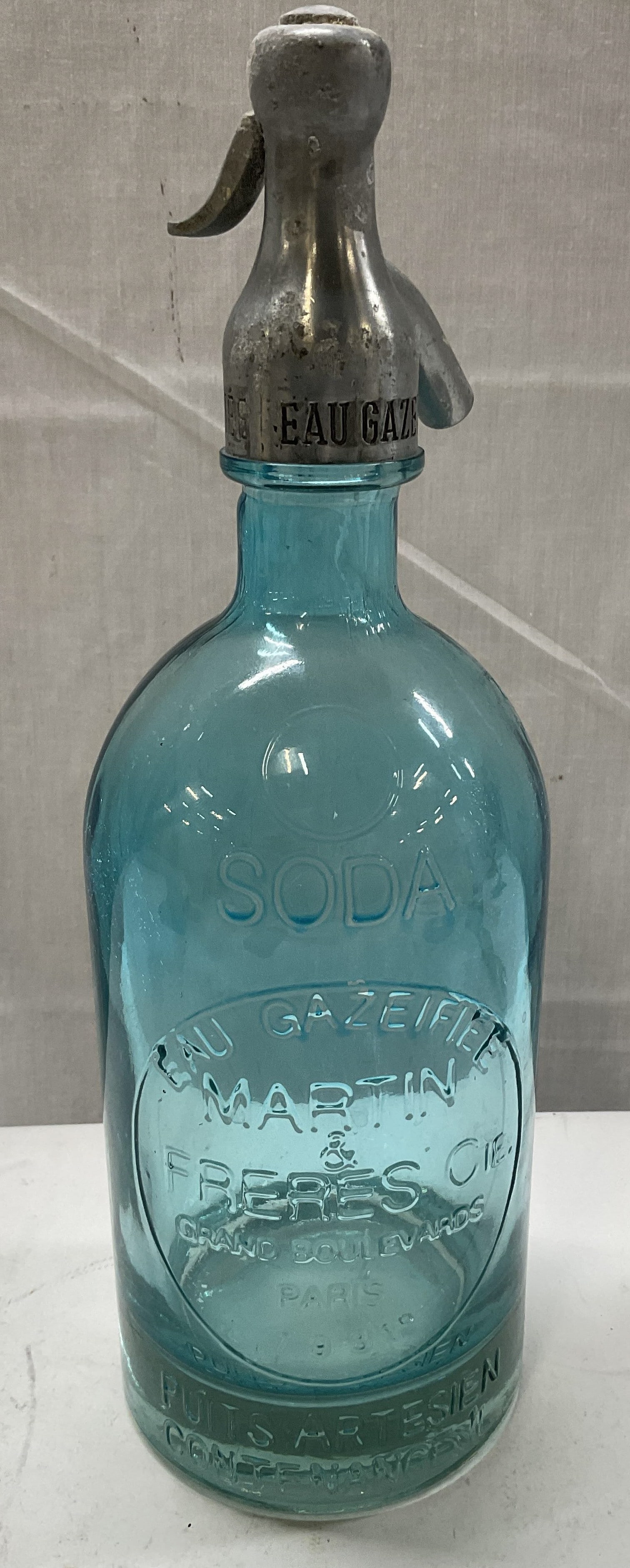 1931 FRENCH Art Glass Seltzer Bottle: 1931 French Blue Art Glass Seltzer Bottle. Metal Top. Reads Eau Gazeifiee Martin & Freres Cie Grand Boulevards Paris 1931. Oxidization and Scratching Present. Measures app 12.5in H x 4in Diam. 1930s, 