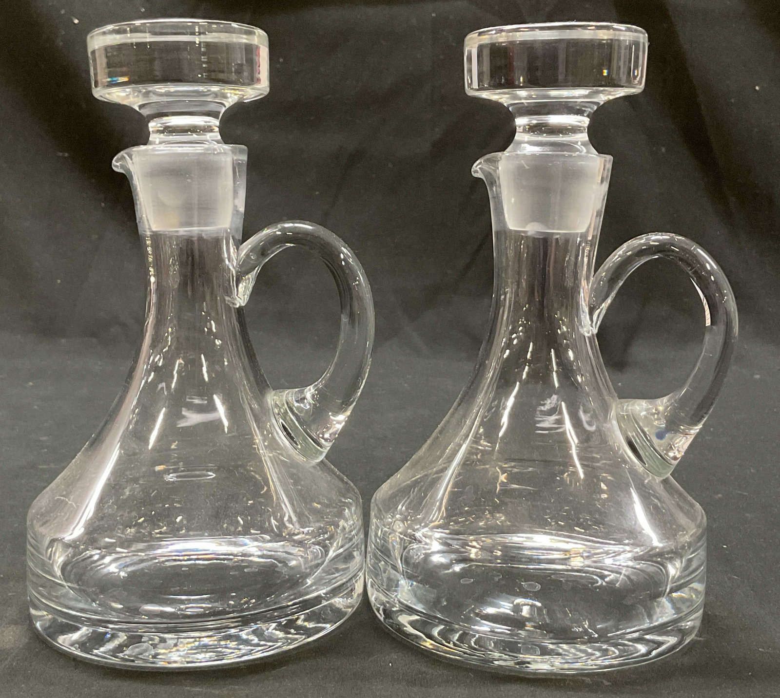 Pair Vintage Glass Cruets W Stopper: Pair of vintage glass cruets. Comes with round stopper. Curved handle and spout. Round wide base. Measures ht approx 7 inches diam approx 4 inches. Scratching. Cruet, tableware, home decor, table deco