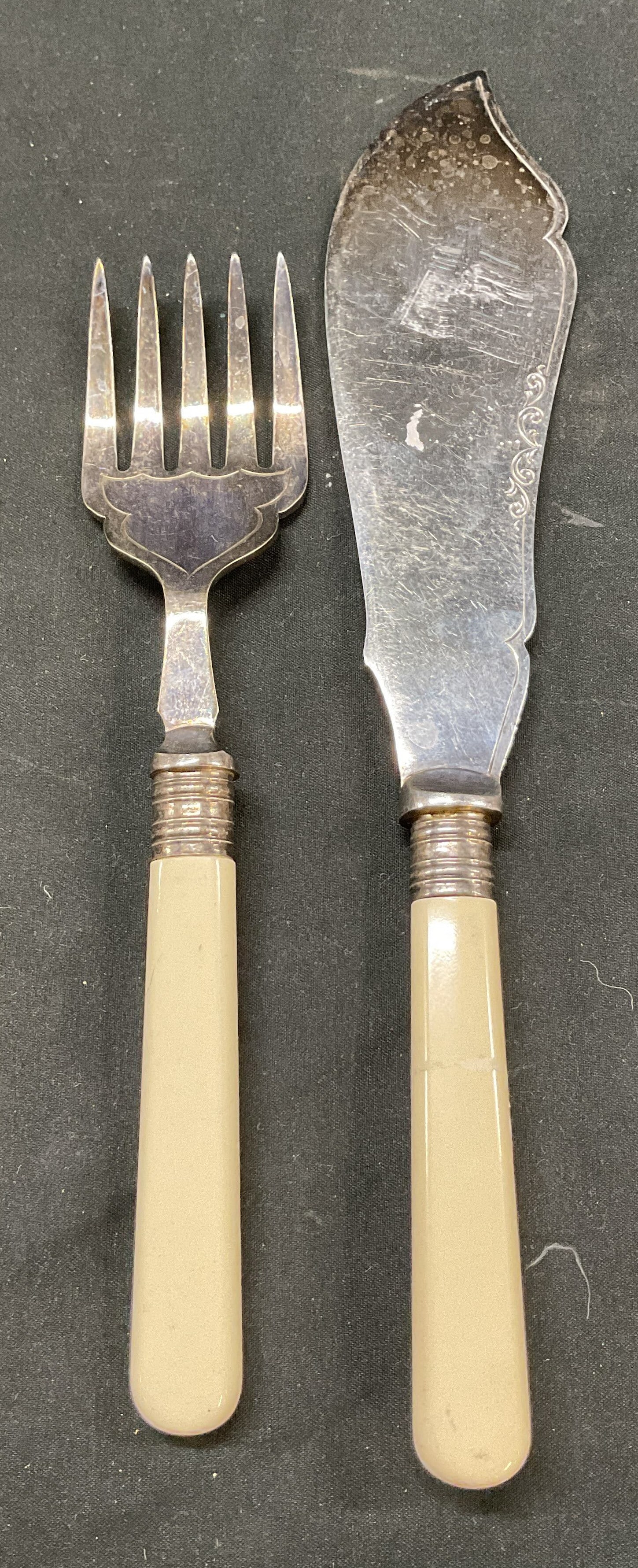 Lot 2 Vintage Silver Plated Serving Fork & Knife: Lot of 2 vintage silver plated serving fork and knife. Makers mark present. Engraved scroll motifs. Bakelite handle. Measures approx 10.5 inches in length. Scratching and wear to surface. Serving fork