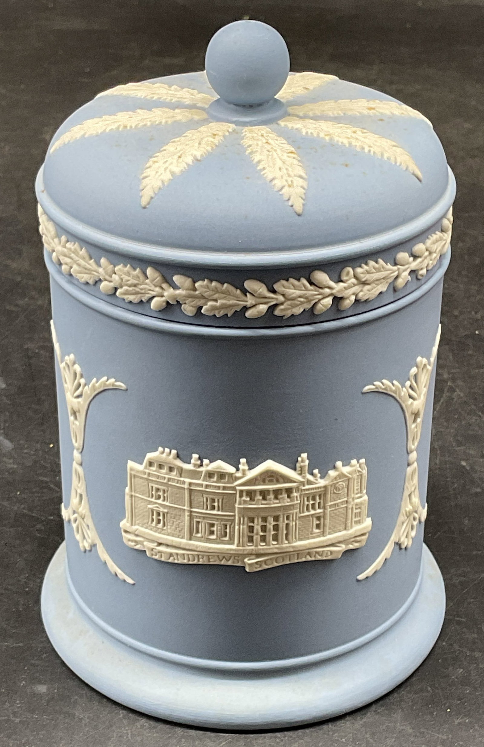Wedgwood Blue Jasperware St Andrews Jar England: Wedgwood blue Jasperware lidded tobacco or candy jar. White bas relief with St Andrews, Scotland and golf motifs. Signed. Made in England. Measures approx. 3.25 x 5 inches. Wear including scratching. 