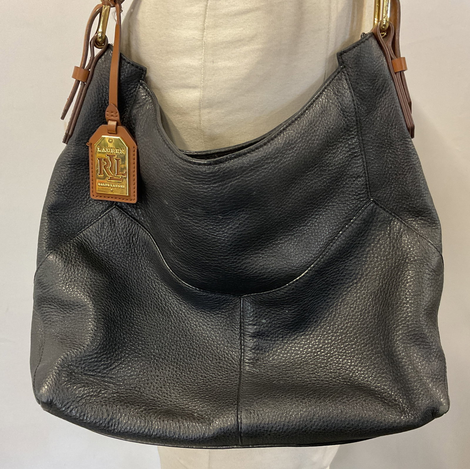 Lauren Ralph Lauren Black Leather Shoulder Bag: Lauren Ralph Lauren black leather shoulder bag. Black body and brown strap. Gold toned buckle and tag accents. Inside compartments. Top zipper. Measures approx 11 x 16 inches. Surface wear consistent 
