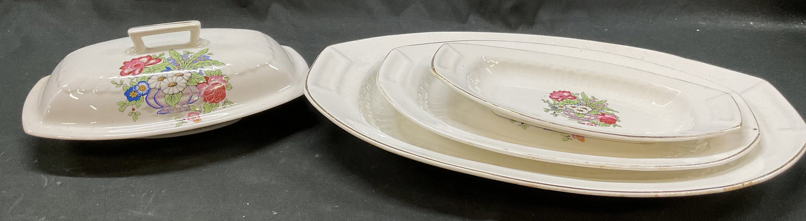 Set 5 Edwin M. Knowles Vitreous China Tableware: 5 piece Edwin M. Knowles vitreous china tableware set. Marked on undersides. Oval shaped serving platters. One comes with lid. Gilt edge. Central floral motif design in varying colors. Measures approx