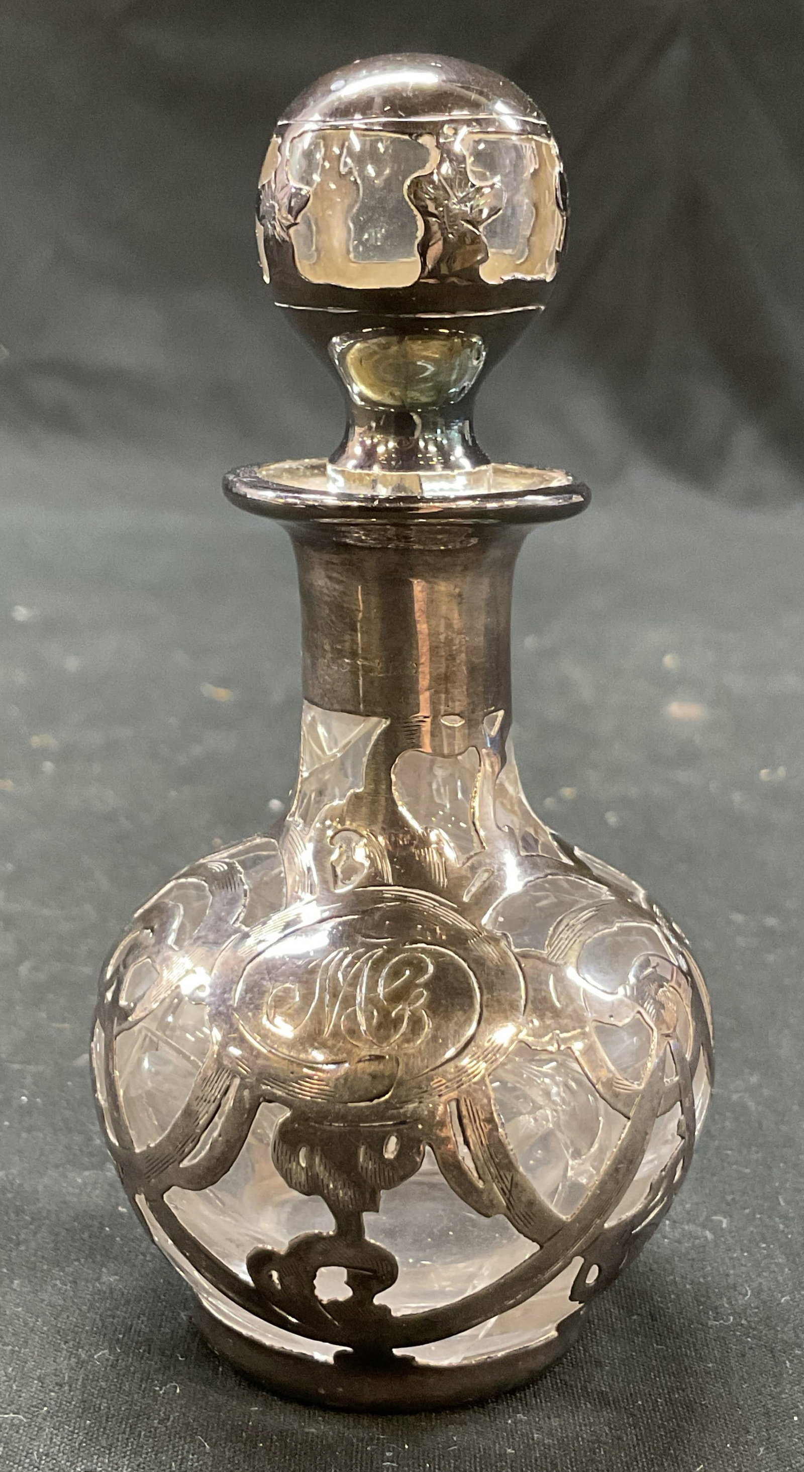 Vintage Glass Sterling Overlay Perfume Bottle: Vintage glass sterling silver overlay perfume bottle. Round body. Spherical stopper. Includes monogram accent, reads illegible. Ornate sterling overlay design. Measures ht approx 4 inches diam approx 