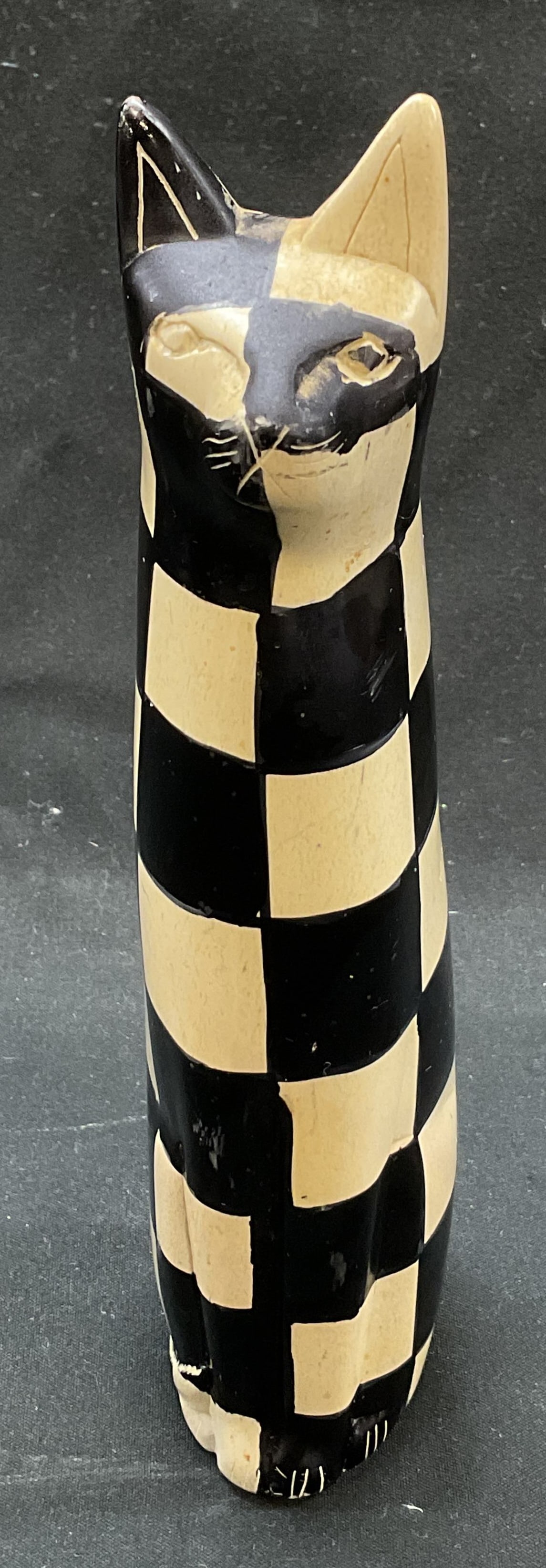 Hand Carved Stone Cat Figure: Hand carved and hand painted stone cat figure. Hand carved features and details. Hand painted black and white checker pattern. Sitting pose. Measures approx 1.5 x 2 x 7.5 inches. Surface wear consiste
