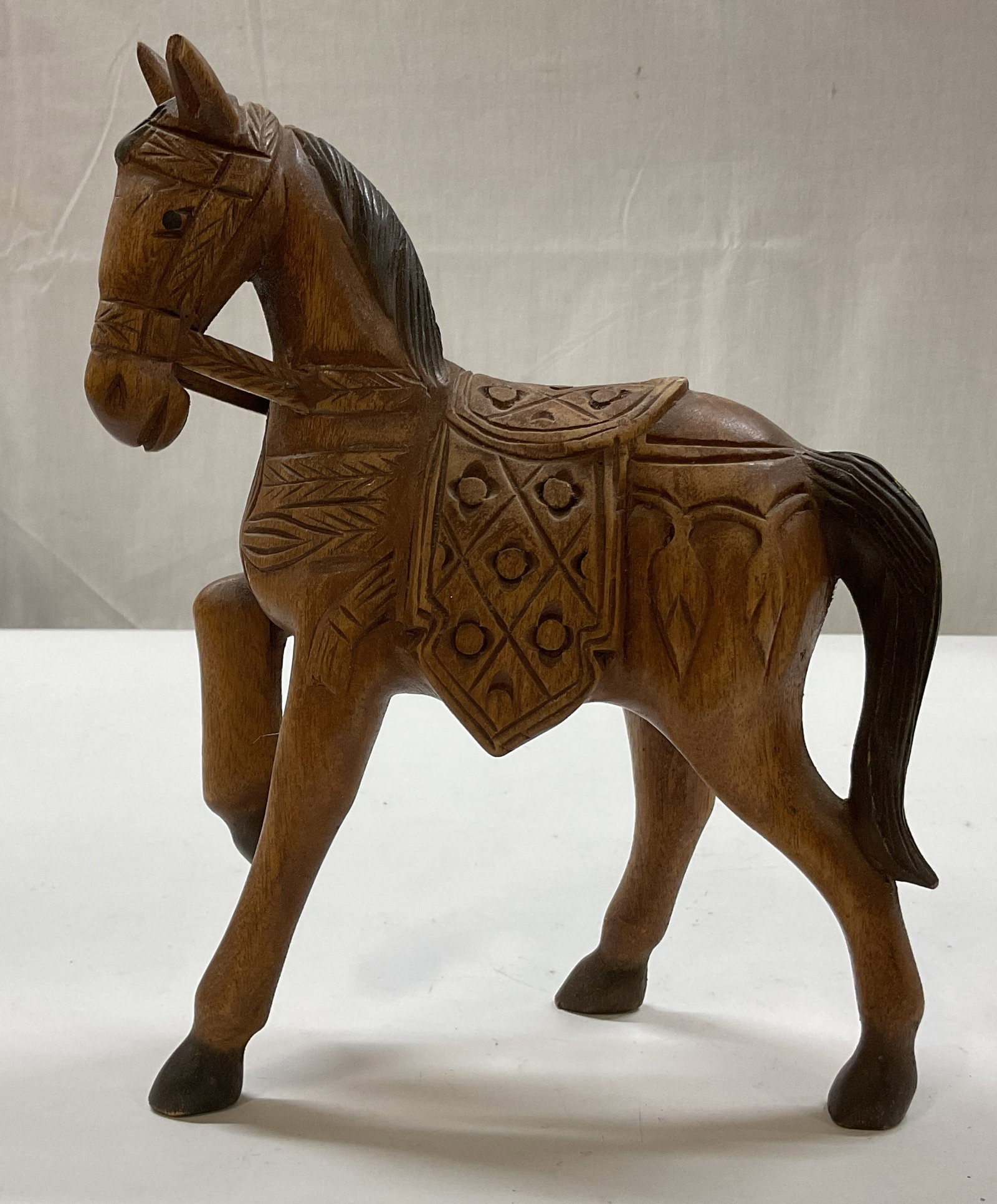 Hand Carved Wooden Horse Figure: Hand carved wooden horse figure. Standing horse figure with one leg up. Hand carved details and features. Carved floral motifs. Measures approx 3.5 x 7.5 x 10 inches. Surface wear consistent with expo
