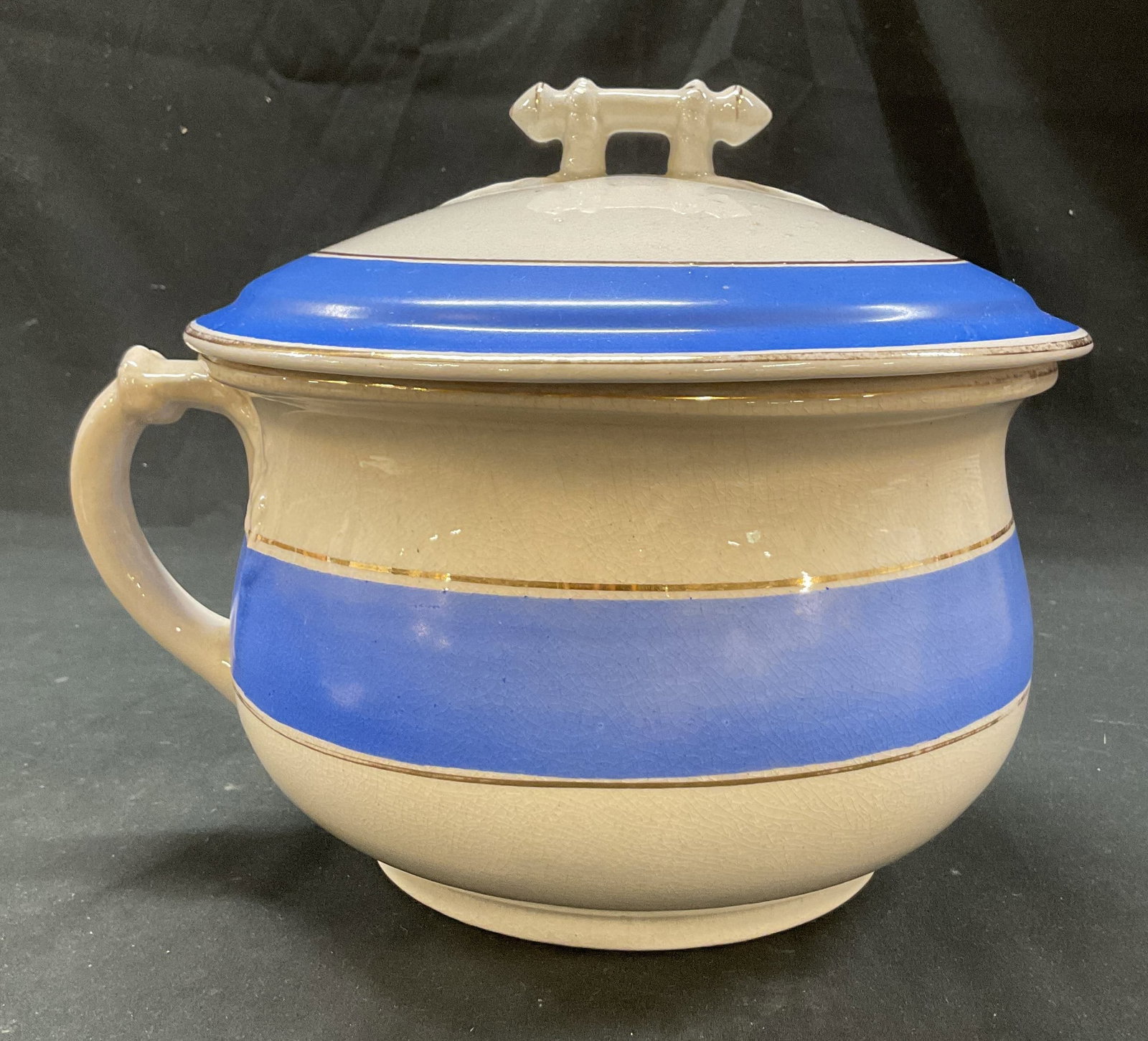 Star Pottery Co Ironstone Lidded Chamber Pot: Star Pottery Co ironstone lidded chamber pot. Marked on underside. Curved handle. Decorative finial on lid. Gilt and blue stripe design. Measures ht approx 8.5 inches diam approx 9 inches. Crazing and