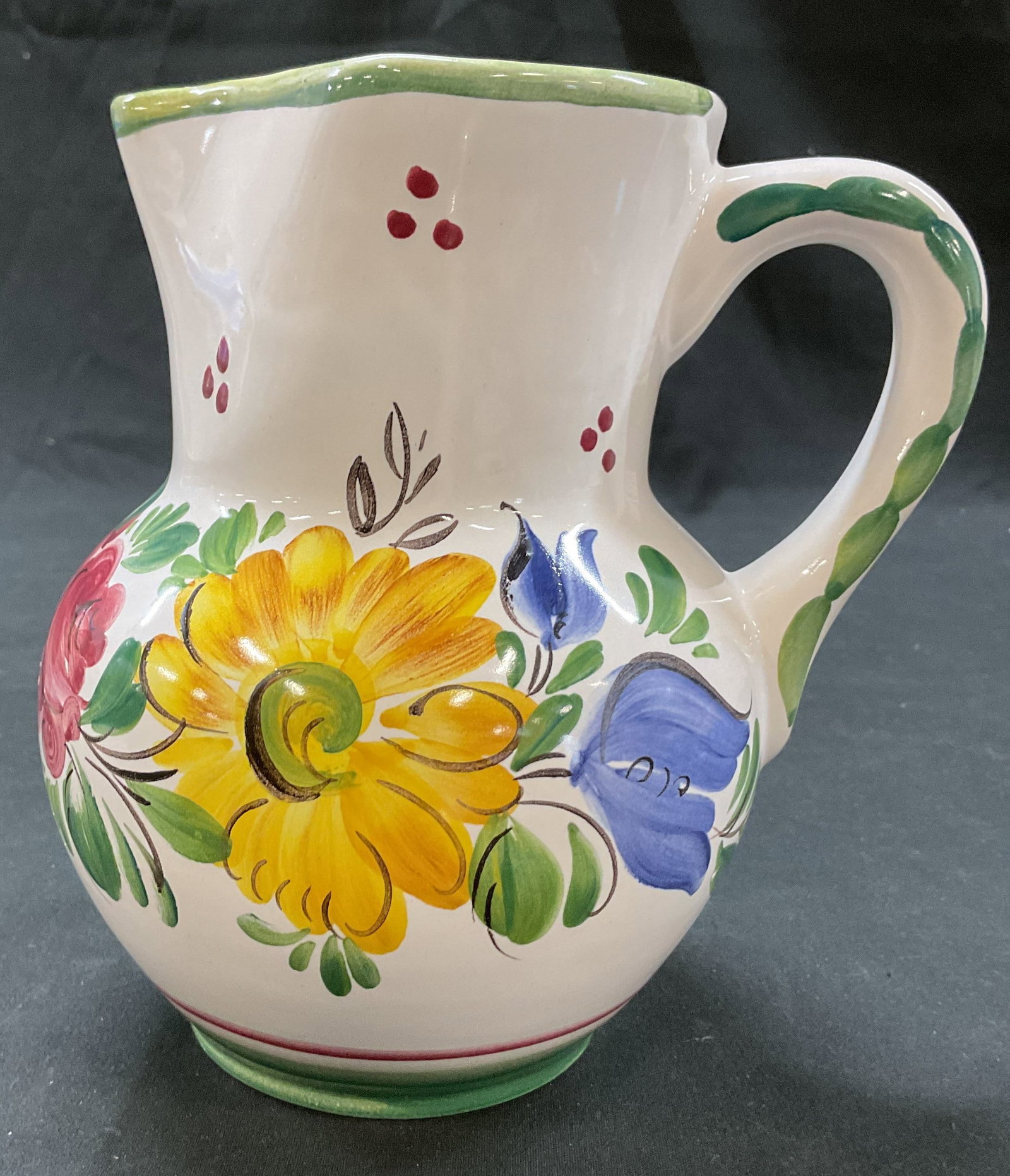 Gmundner Keramik Ceramic Painted Pitcher Austria: Gmundner Keramik ceramic hand painted pitcher. Marked on underside. Made in Austria. Round base and bulbous body. Curved spout and handle. Hand painted floral motifs in varying colors. Measures ht app