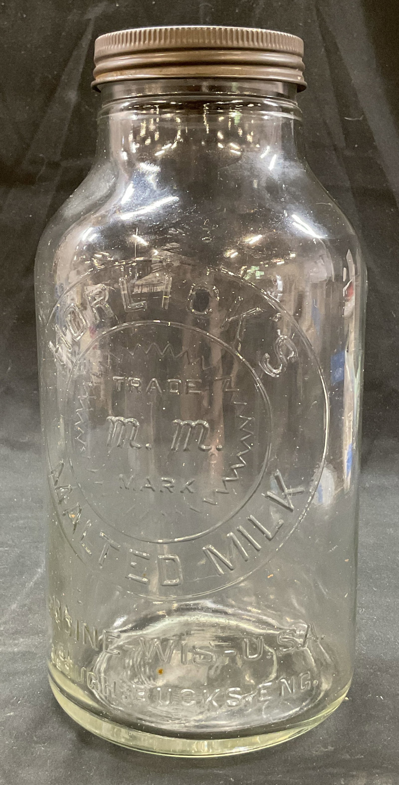 Vtg Horlicks Glass Malted Milk Jar USA England: Vintage Horlicks glass malted milk jar. Marked on surface, reads Horlicks Trade Mark Malted Milk Racine Wis USA Slough Bucks Eng. Comes with lid. Bulbous shape and narrow neck. Measures ht approx 11 i