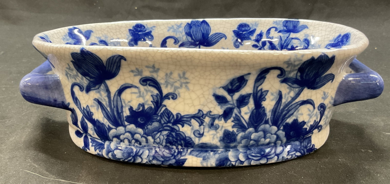 The Bombay Company Blue & White Planter: The Bombay Company blue and white porcelain planter. Marked The Bombay Company on underside. Oval shaped with handles on either side. Blue and white floral motifs. Measures approx 5.5 x 9 x 3 inches. 