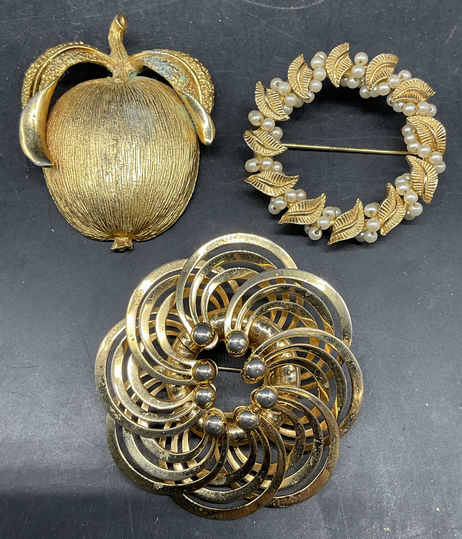 Lot 3 Vintage Gold Tone Apple Brooch +: Lot of 3 vintage gold tone brooches. Apple, faux pearls, and flower. Largest measures approx. 2.25 inches long. Some scratching. Jewelry, estate jewelry, costume jewelry, cocktail jewelry, fashion jew