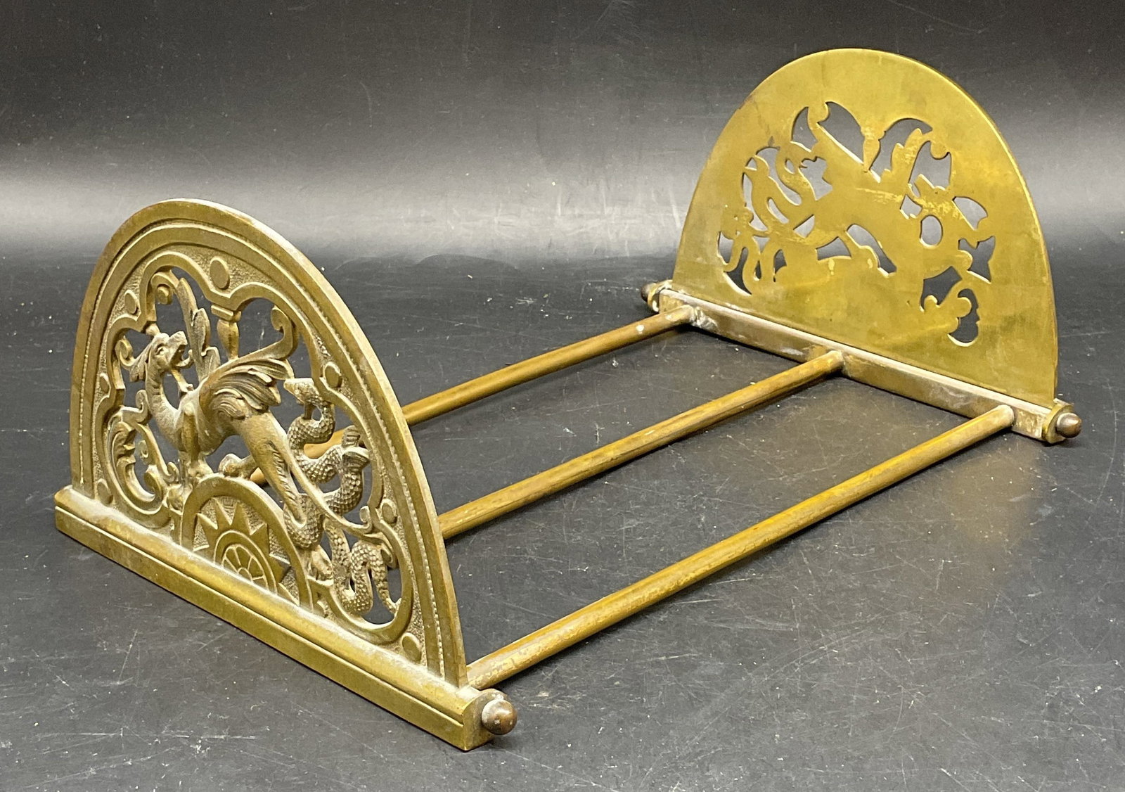 Art Nouveau Style Dragon Brass Book Slide Rack: Art Nouveau style brass book slide rack. Ornate mythological dragon and serpent motifs. Expandable rack, ends fold down. Total dimensions measures approx. 20 x 7 x 4.5 inches. Wear including patina an