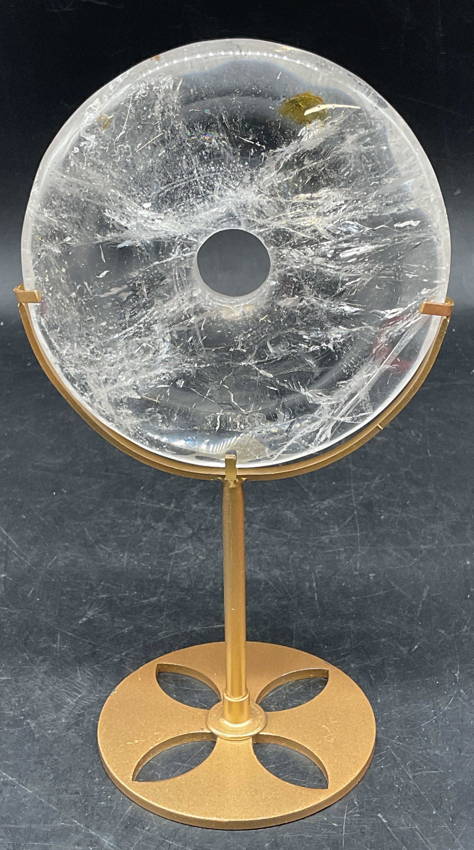 Clear Quartz Semiprecious Disc with Stand: Clear quartz polished disc with a gold tone stand. Disc measures approx. 4 inches wide. Stand measures approx. 5.25 inches tall. Total weight of stone 381.7 grams. Some scratching and chips. Quartz di
