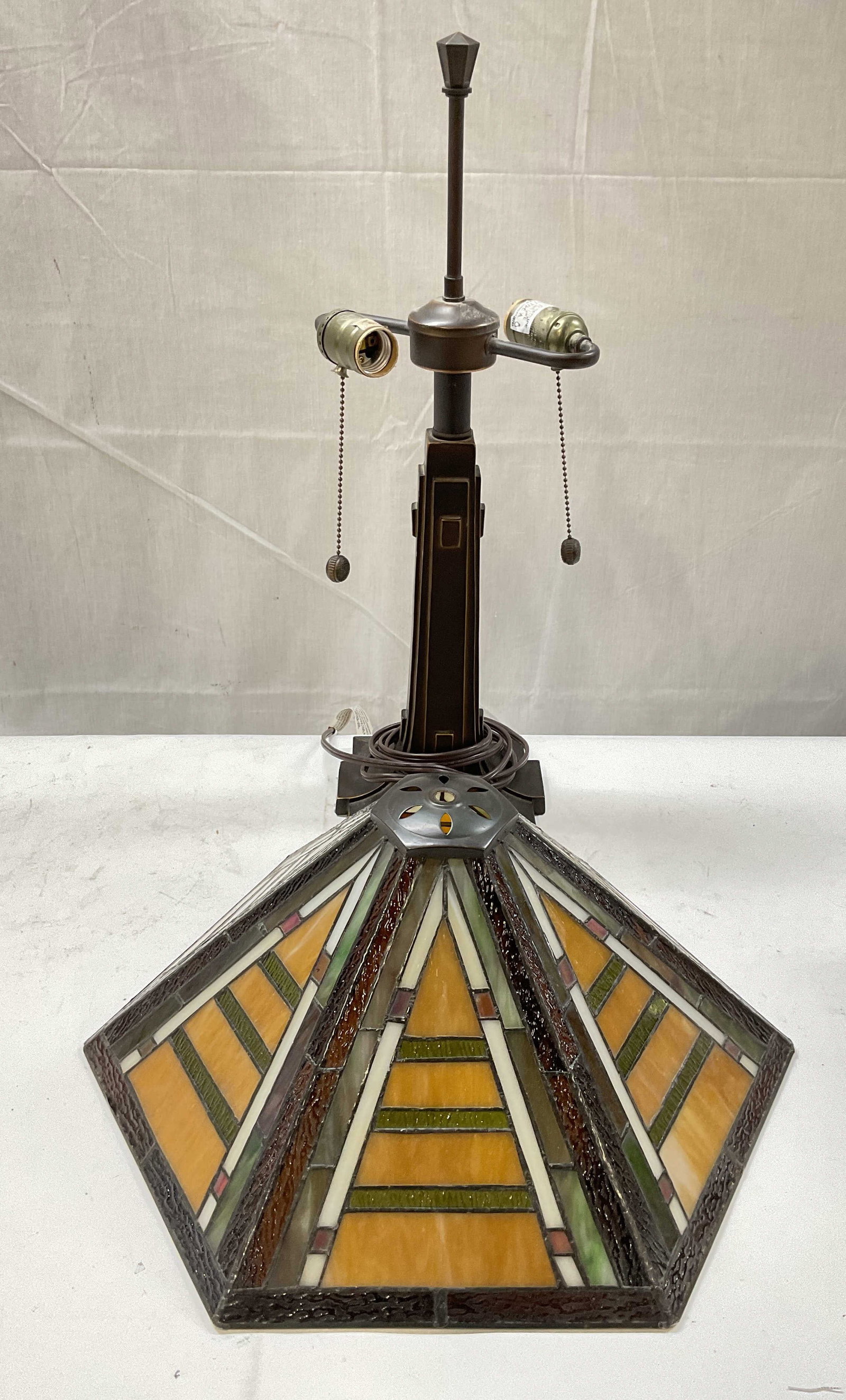 Art Deco Style Slag Glass Bronze Patina Lamp: Art Deco style lamp. Bronze patina metal geometric base with a neutral toned hexagonal shaped slag glass lampshade. Base measures approx. 6.25 x 6.25 x 22 inches. Shade measures approx. 17 inches wide
