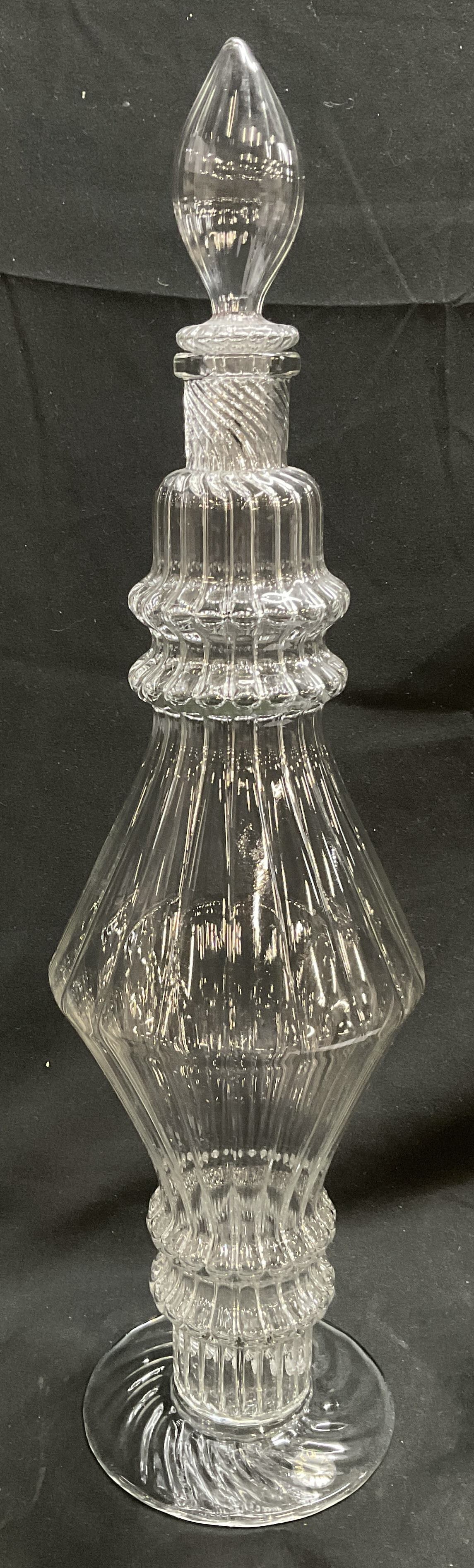 ANTIQUE Hand-Blown Clear Glass Decanter ROMANIA: Antique Hand-Blown Clear Glass Ring Neck Decanter. Faceted Body. Spire-Style Stopper. Made in Romania. Condition Consistent With Exposure. Measures to Stopper app 18in H x 5in Diam. Antique Glassware,