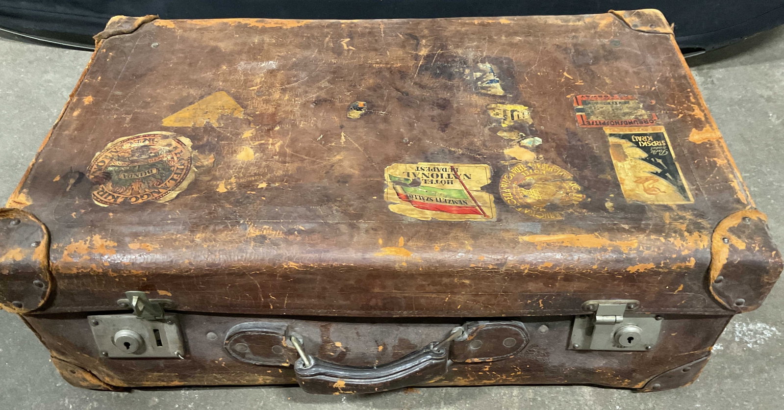 Antique Brown Leather Suitcase w Travel Patches: Antique leather suitcase with multiple travel patches, blue lining with leather trim pockets and insert tray, has worn leather corners, metal latches, and travel stickers from early 20th century,