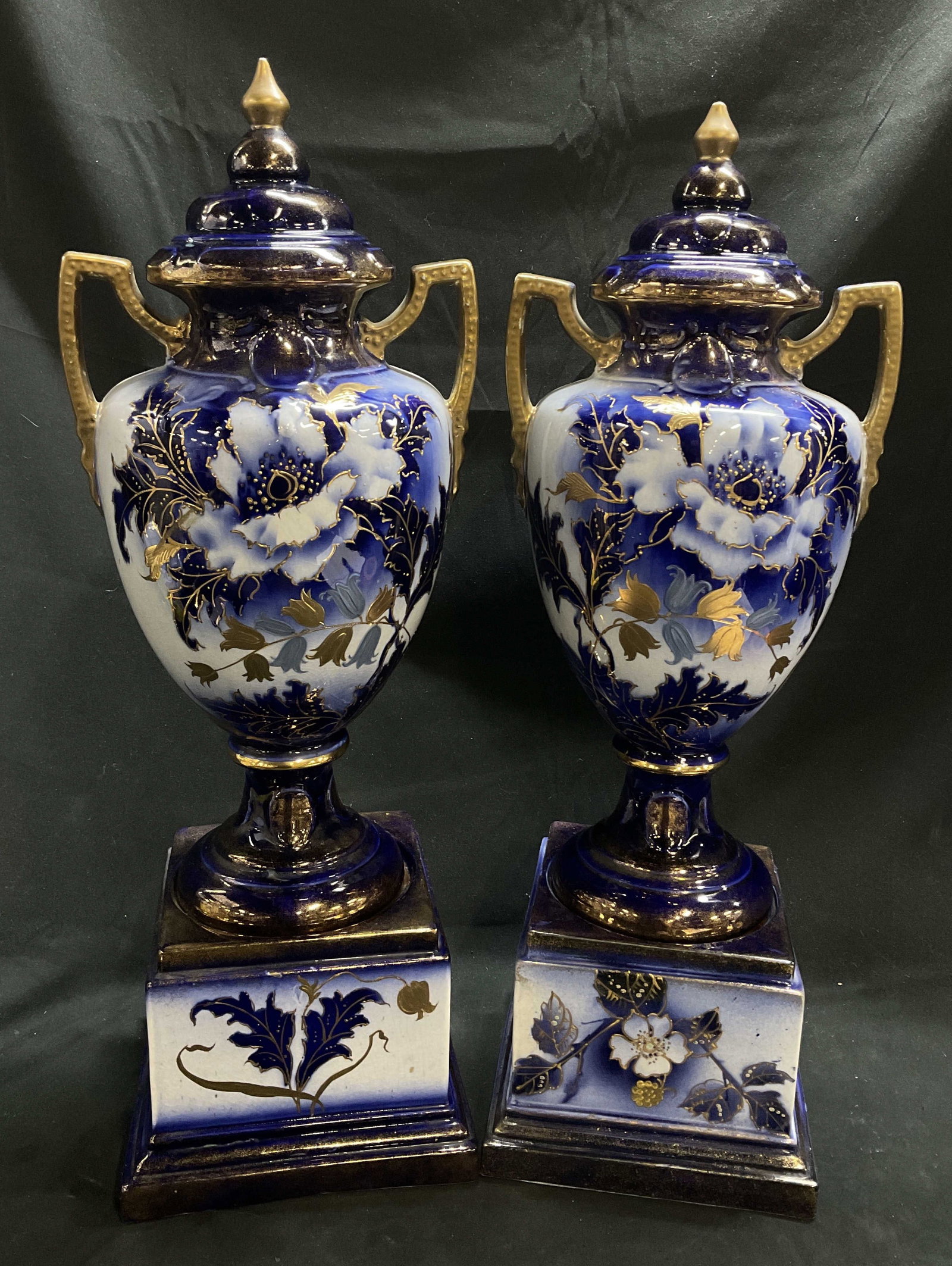 Pair ANTQ 22.75in Bohemian Cobalt Porcelain Urns: Pair of Antique Bohemian Cobalt Blue Porcelain Urns. Sit on Rectangular Bases. Blue, White, and Gilt Floral Designs. Peeling and Crazing Present. Measures app 22.75in H x 7.25in L. Antique Urns, Bohem