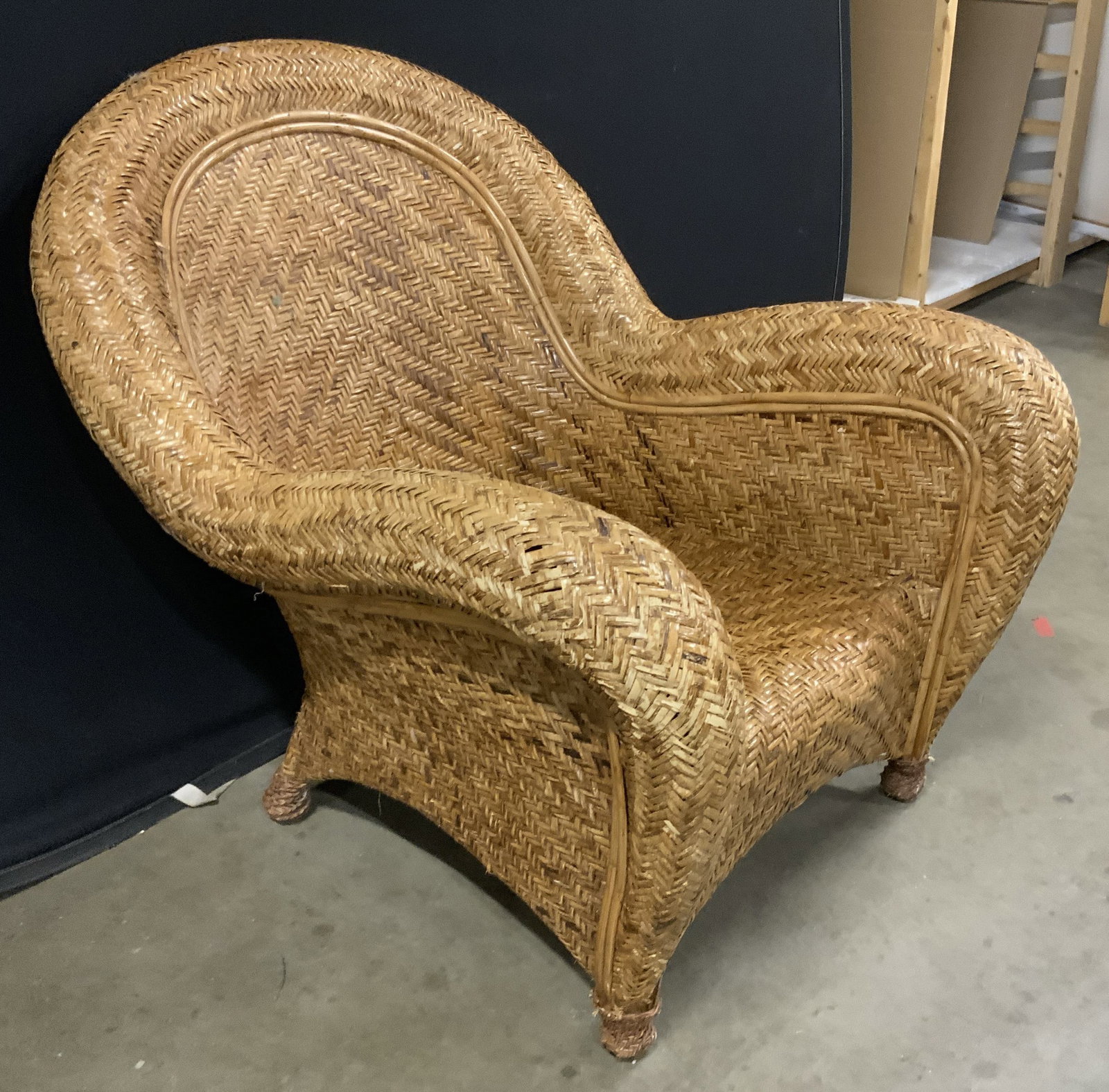 Woven Carmel Toned Rattan Arm Chair: Has seat cushion. Woven rattan arm chair, has wide arched back, large splayed armrests, tapers to bun feet, measures ht app 32 inches, width app 32 inches, depth app 41 inches