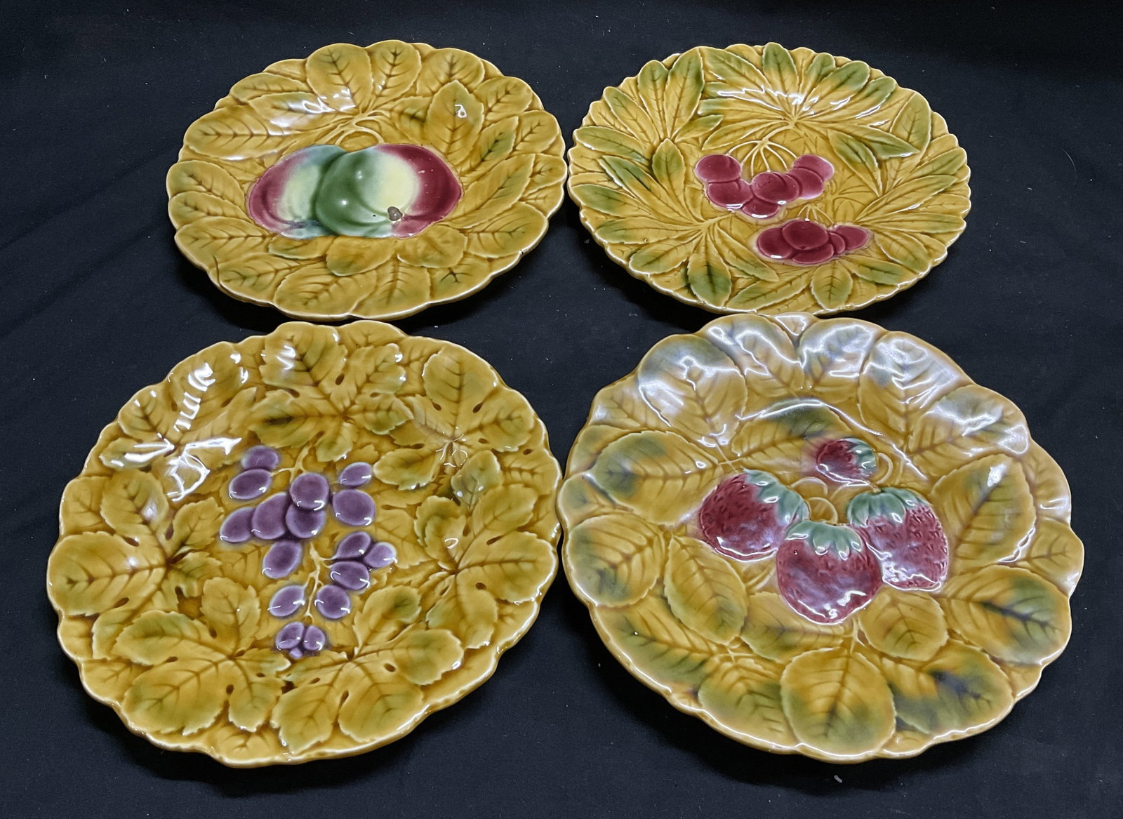 Lt4 VTG PV FRANCE Fruit Majolica Pottery Plates: Lt4 Vintage Circa 1920s-1970s Peasant Village Fruit Majolica Pottery Plates. Distinct Yellow Ground with Sculpted Leaves and Central Fruit Motifs. Includes Cherries, Grapes, Mangoes, and Strawberries.