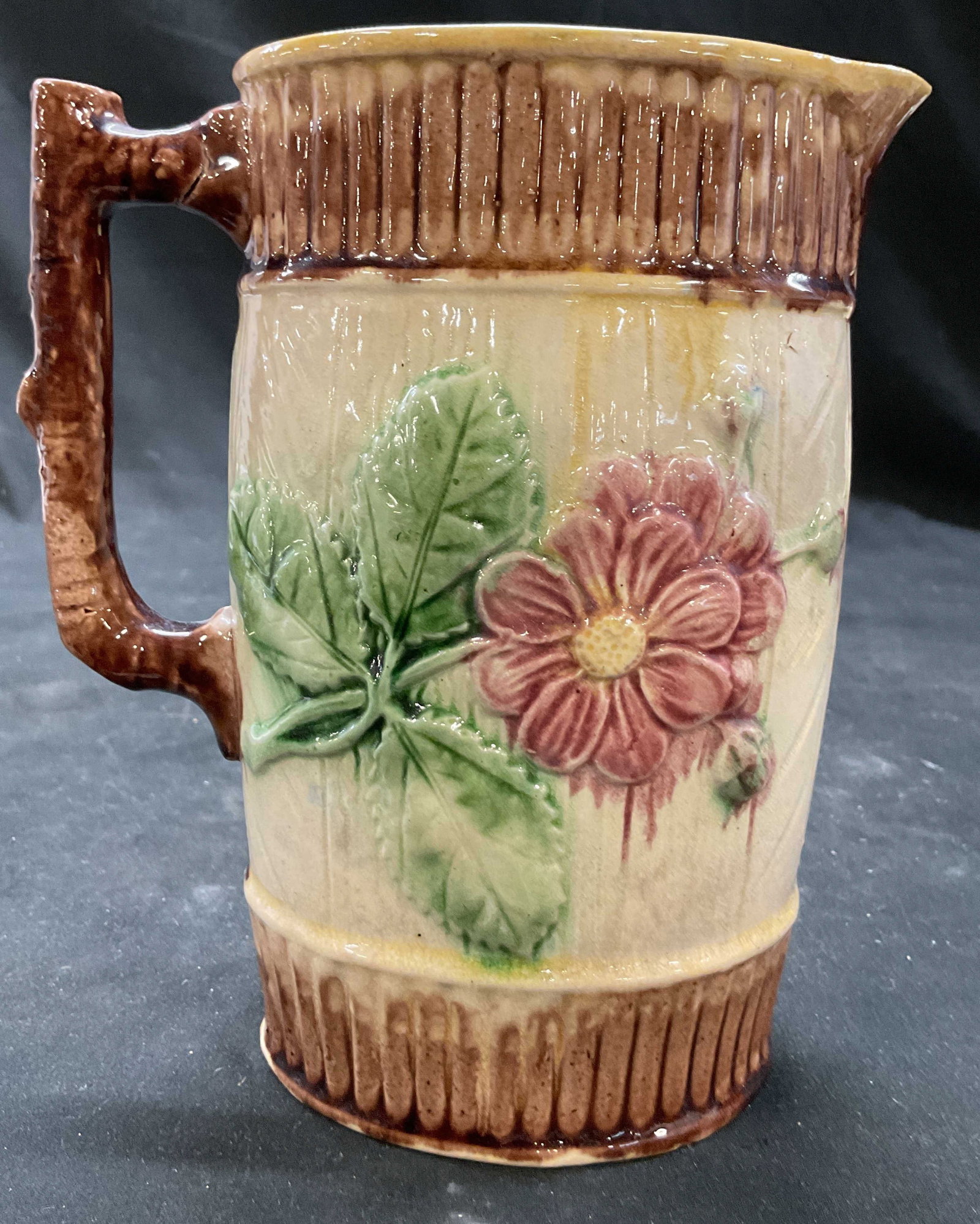 Antique English Majolica Ceramic Pitcher: Antique English Majolica Pitcher from late 1800s features a floral and basket weave pattern, the colors of pink greens and browns are used on a cream toned body, faux bois handle, and unusual oblong s