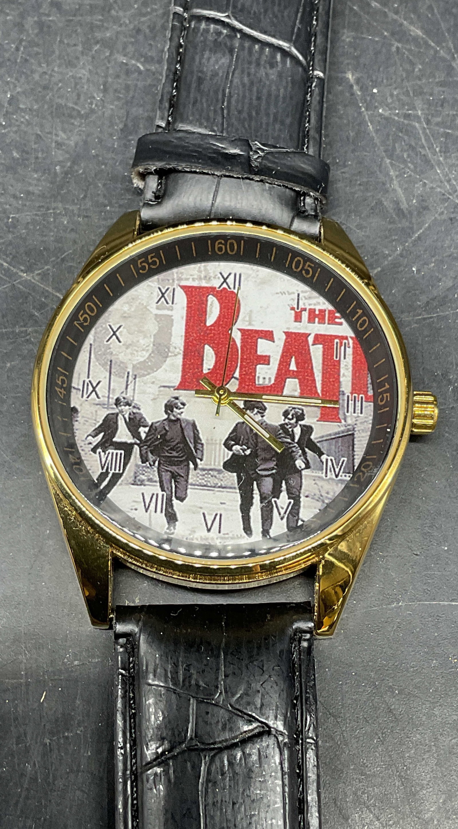The Beatles Gold Tone Faux Leather Watch: Gold and black faux leather watch with The Beatles graphic print dial. Measures approx. 9 inches long. Not tested. Some scratching. Jewelry, estate jewelry, costume jewelry, cocktail jewelry, fashion 