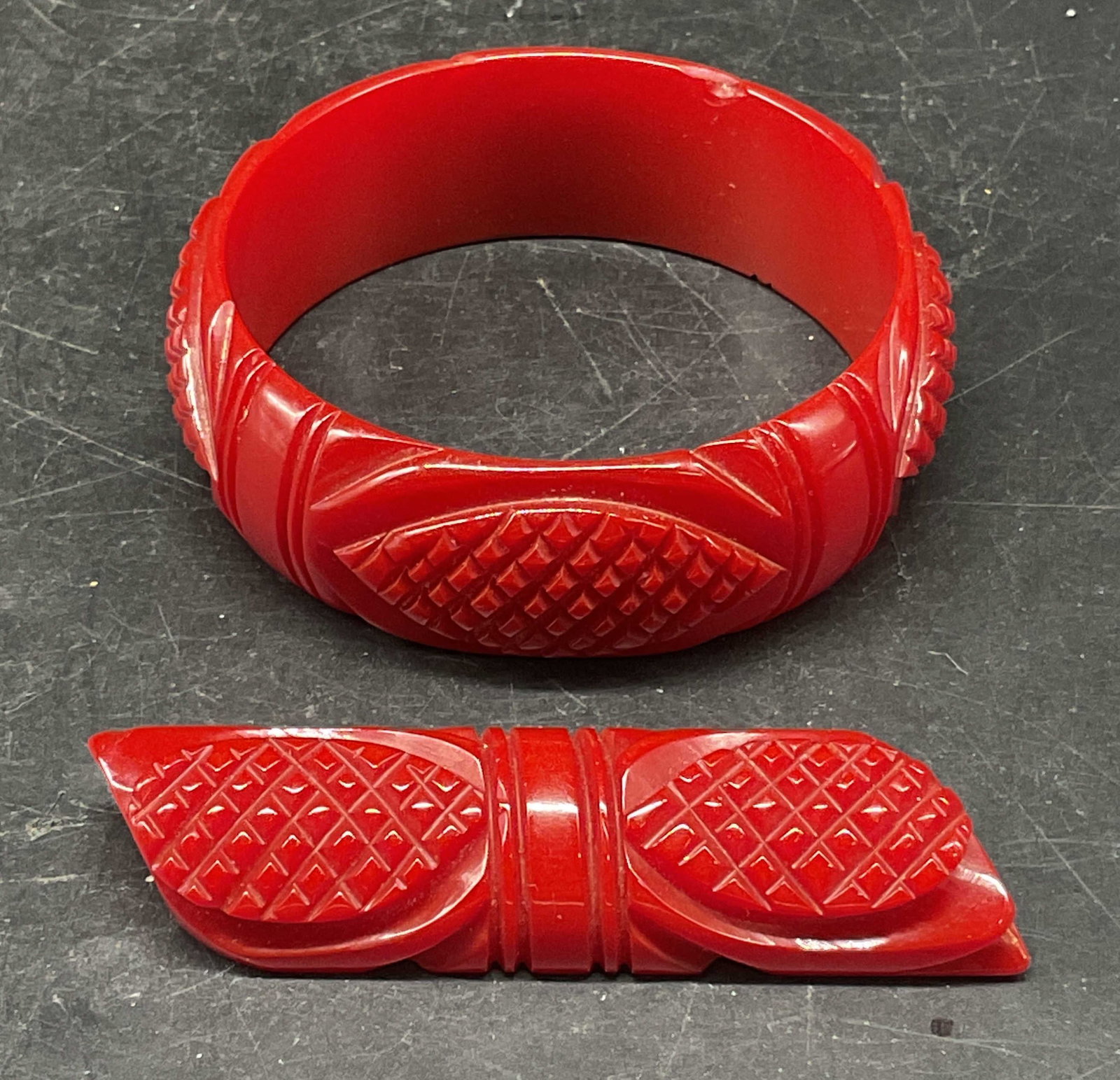 Lot 2 Vintage Red Lucite Bangle & Brooch: Lot of 2 matching vintage red lucite jewelry pieces. Bangle bracelet and brooch. Brooch measures approx. 3.25 x 1 inches. Bangle measures approx. 2.5 inches wide. Chip to bangle. Some scratching. Jewe