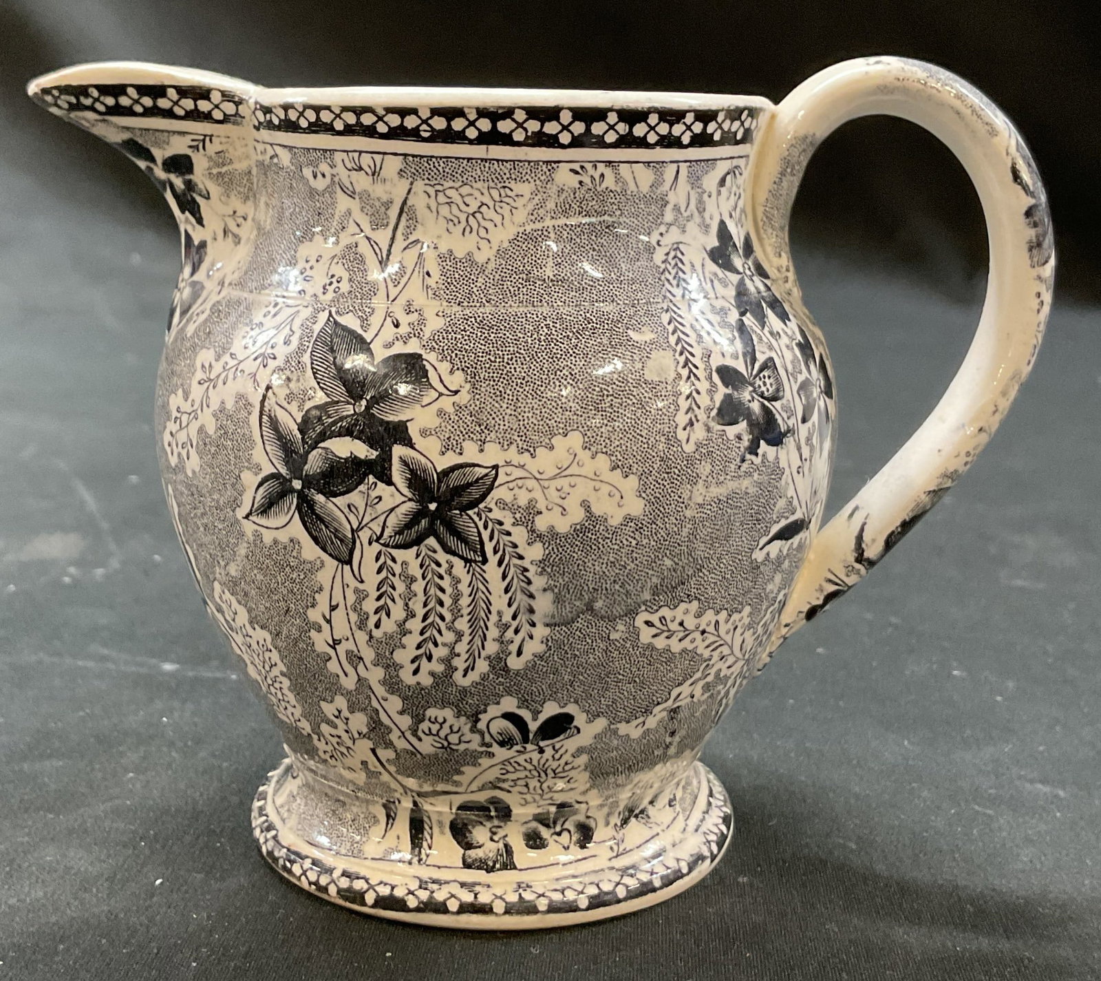 Vintage Black & White Floral Porcelain Creamer: Vintage black and white floral porcelain creamer. Short pedestal base. Curved handle and spout. Black and white floral motifs. Measures ht approx 4 inches diam approx 3.5 inches. Scratching. Creamer, 
