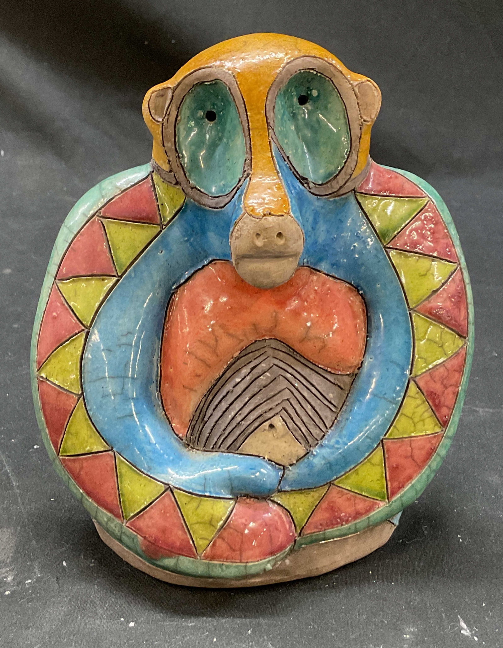 Fenix Raku Pottery Figure South Africa: Fenix Raku pottery ceramic figure. Hand made in South Africa. Sitting animal like figure. Hand painted geometric patterns in varying colors. Carved details. Measures approx 4 x 6 x 6 inches. Scratchin