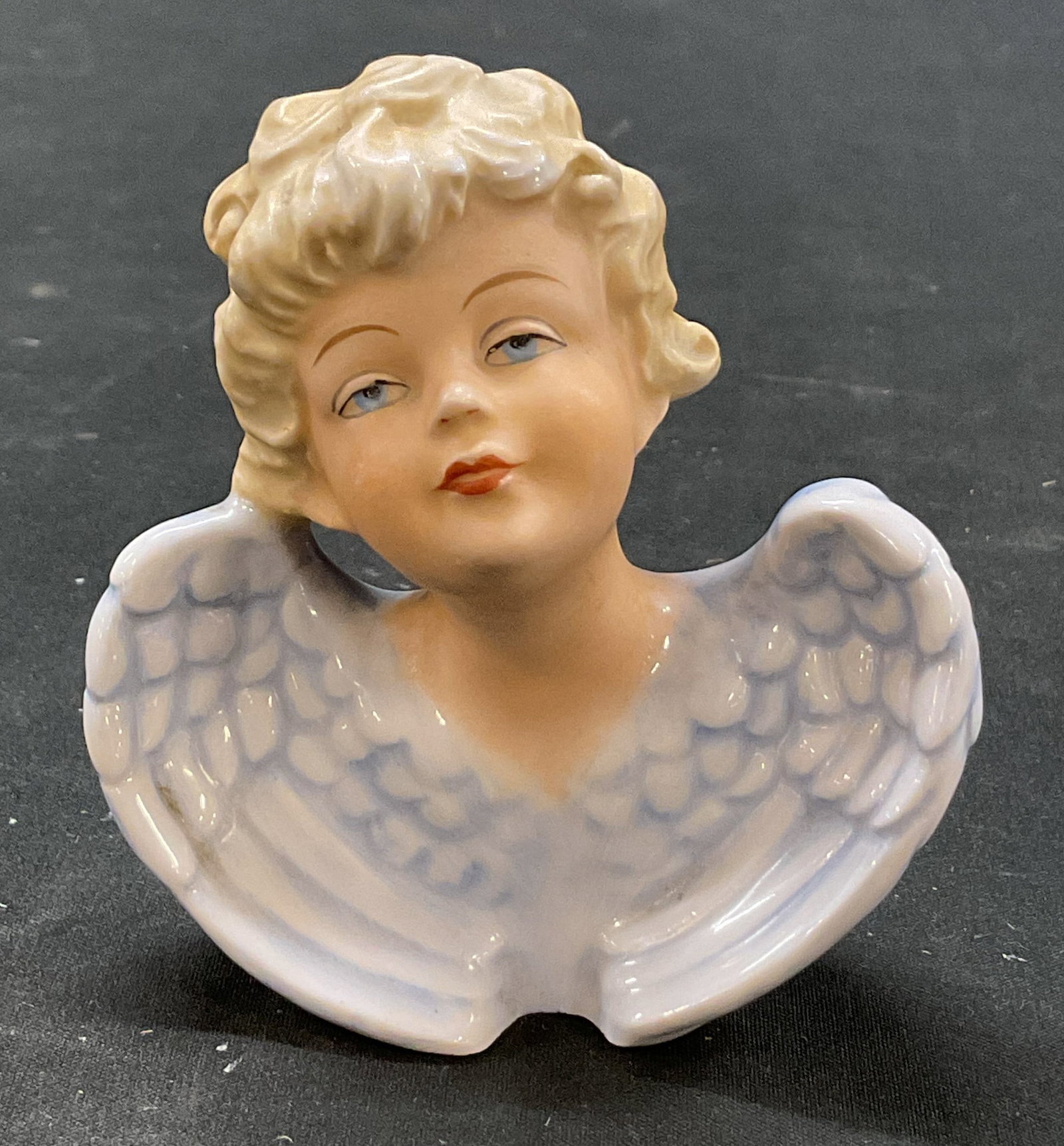 Alfred Orlik Porcelain Cherub Figure Germany: Alfred Orlik porcelain cherub figure. Marked Germany on underside. Cherub figure with blue wings, blonde hair, blue eyes, and red lips. Hand painted. Textured surface and scalloped edge. Measures appr