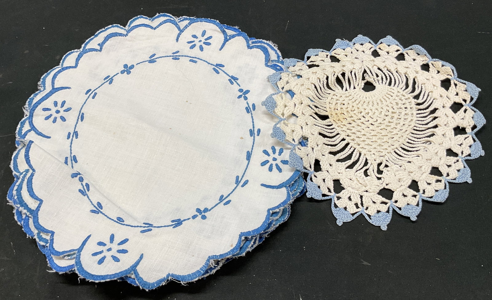 Grp Lot 12 Vtg Blue Embroidered Table Linens: Group lot of 12 vintage blue embroidered table linens. 11 circular placemats with scalloped trim and blue embroidered floral motifs. One crocheted doily in blue and white. Size vary. Largest measures 