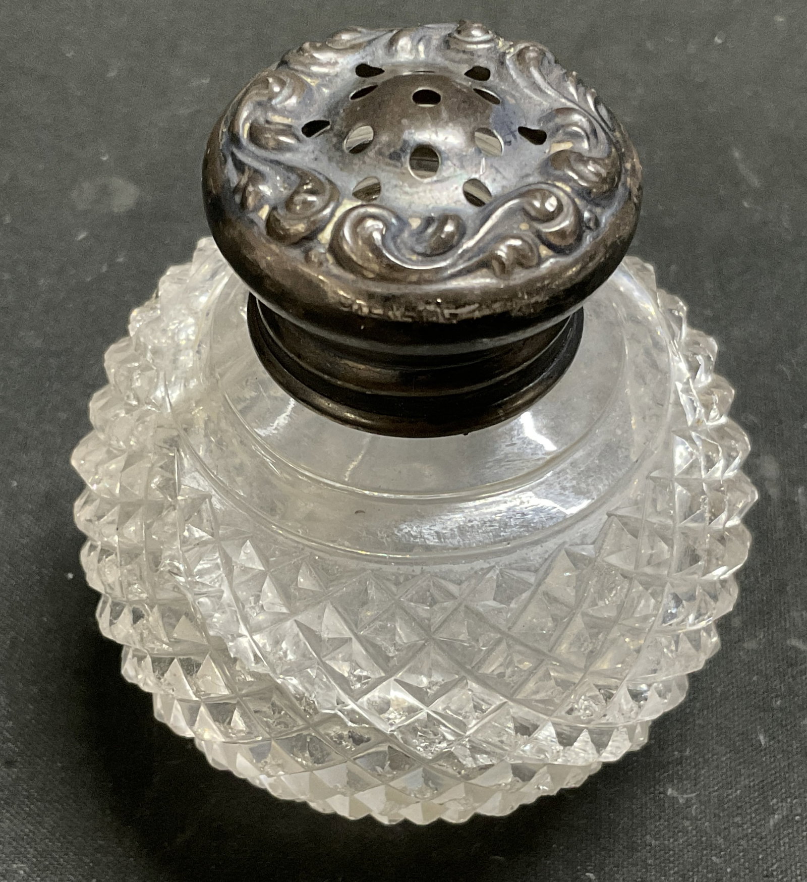 ANTQ STERLING Lidded Hobnail Glass Shaker: Antique Clear Hobnail Glass Salt and Pepper Shaker with Sterling Silver Floral Scroll Design Lid. Marked Sterling. Cracks in Glass and Tarnishing Present. Measures app 3in H x 2in Diam. Sterling Cap W