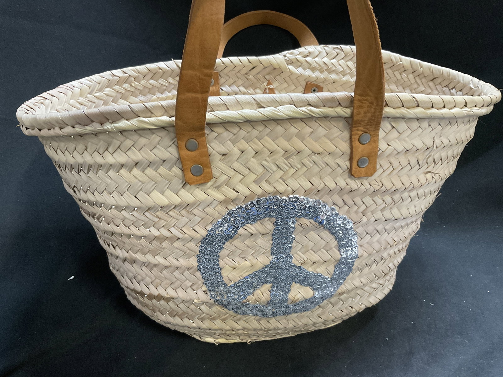 Buckle Up Woven Palm Leaf Peace Sign Tote MOROCCO: Buckle Up Woven Palm Leaf Tote Bag. Silver-Toned Sequin Peace Sign on Front. Brown Leather Handles and Star-Shaped Tag. Made in Morocco. Condition Consistent With Exposure. Measures app 9in H x