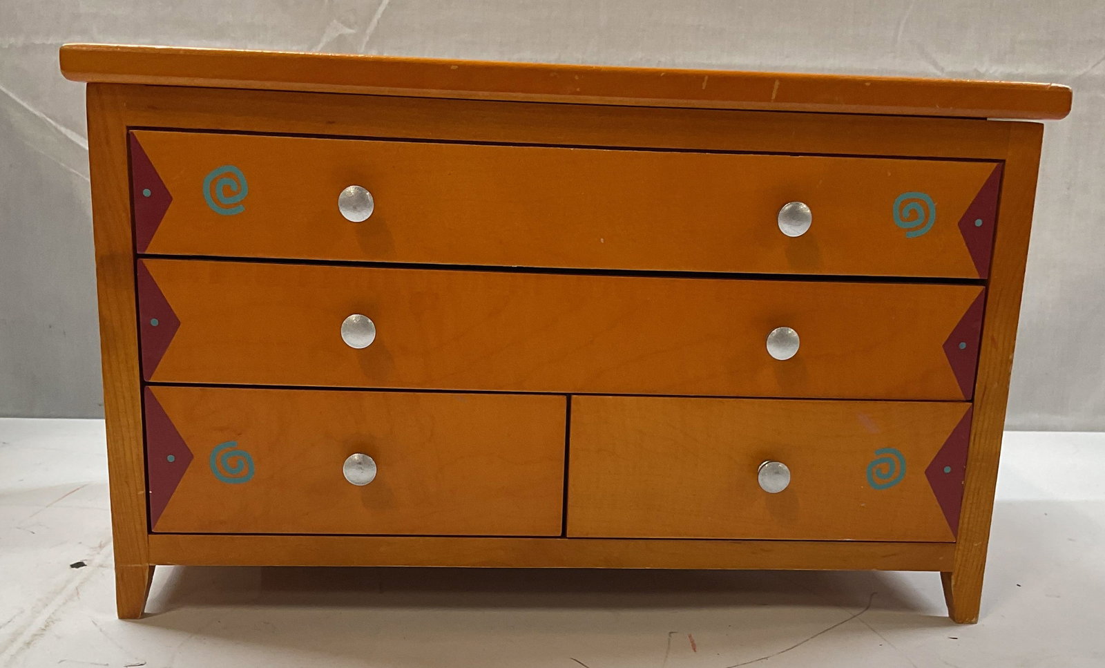 Painted Wooden Multi Drawer Jewelry Box: Wooden Jewelry box. Orange finish with pink and blue accents on the front 3 drawers.( top Knobs are decorative ) Sliver hardware and grey velvet interior. Top hatch features a mirror ,ring slots and s