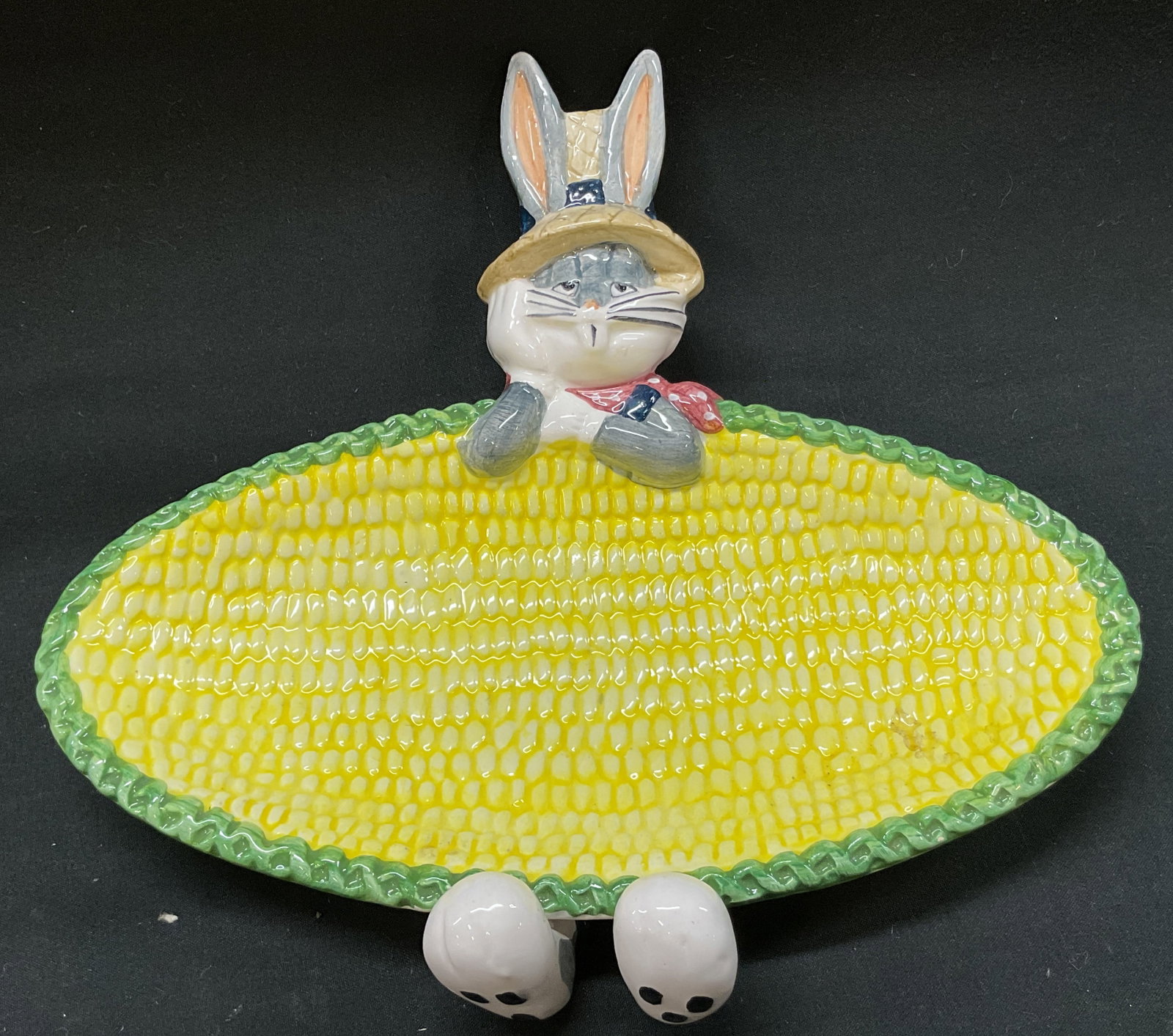 Vtg. 1995 Looney Tunes Buggs Bunny Corn Cob Dish: vintage. 1995 Looney Tunes Buggs Bunny Corn Cob Dish. Buggs Bunny wearing sculpted straw farmers hat and red neck kerchief. White paws molded over rim. Feet peek out beneath bottom edge. Serving surfa